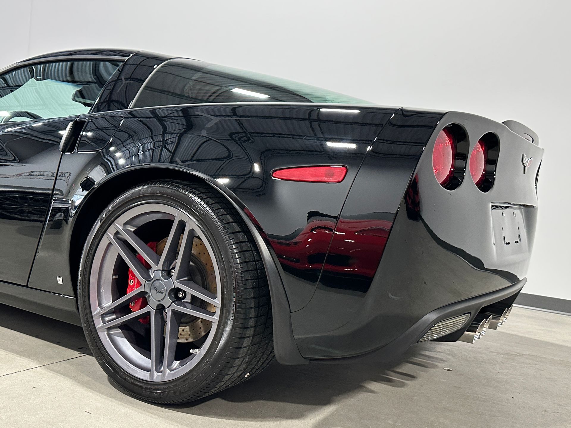 Black Chevrolet Corvette sports car, rear quarter view, with red brake calipers.