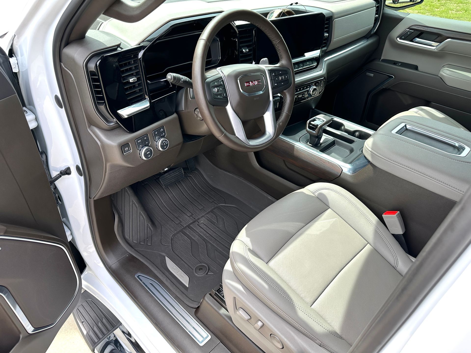 Interior of a white GMC truck, showing the driver's seat, dashboard, and center console.