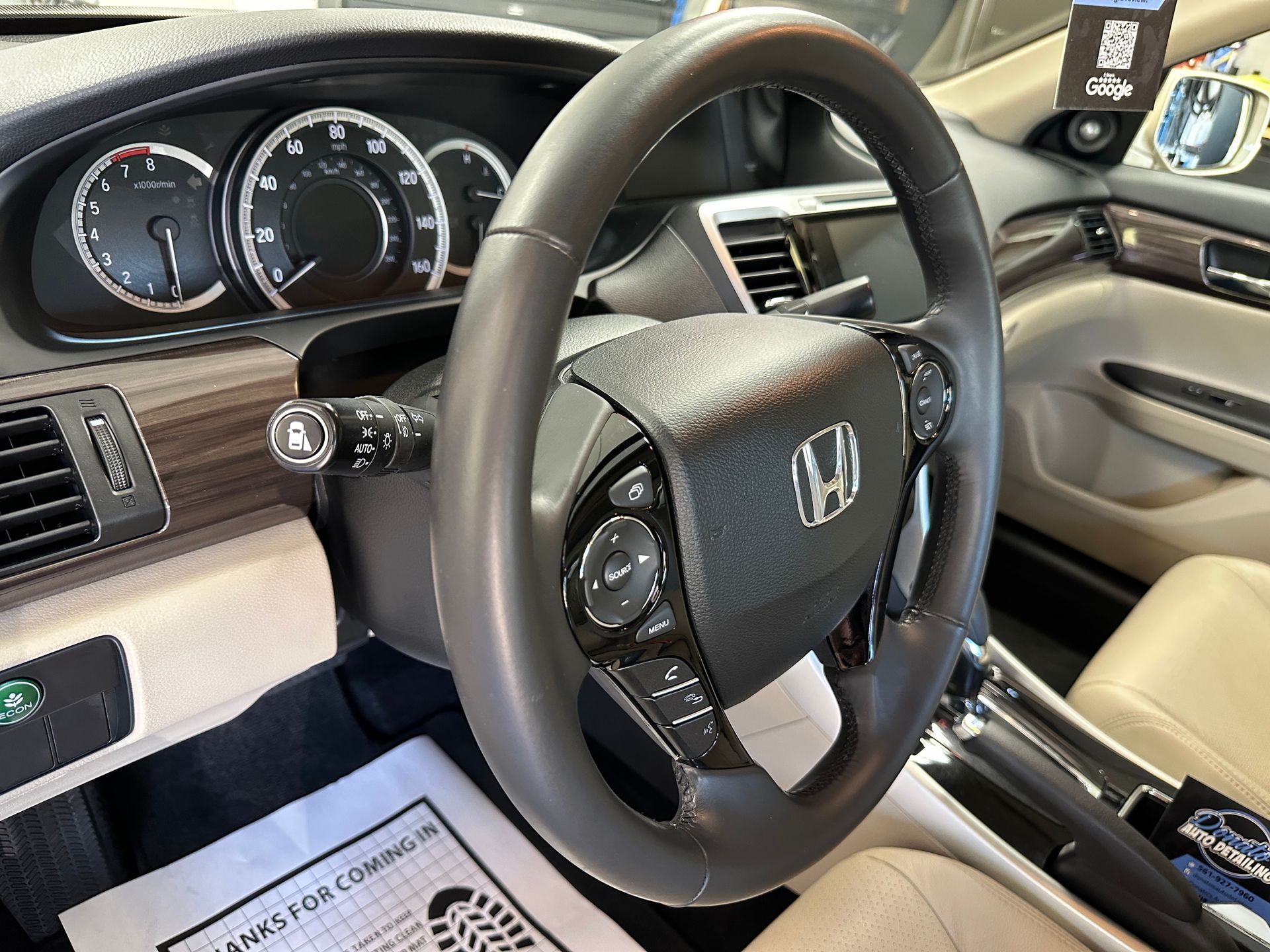 Steering wheel and dashboard of a Honda Accord, with gauges, controls, and wood-grain trim.