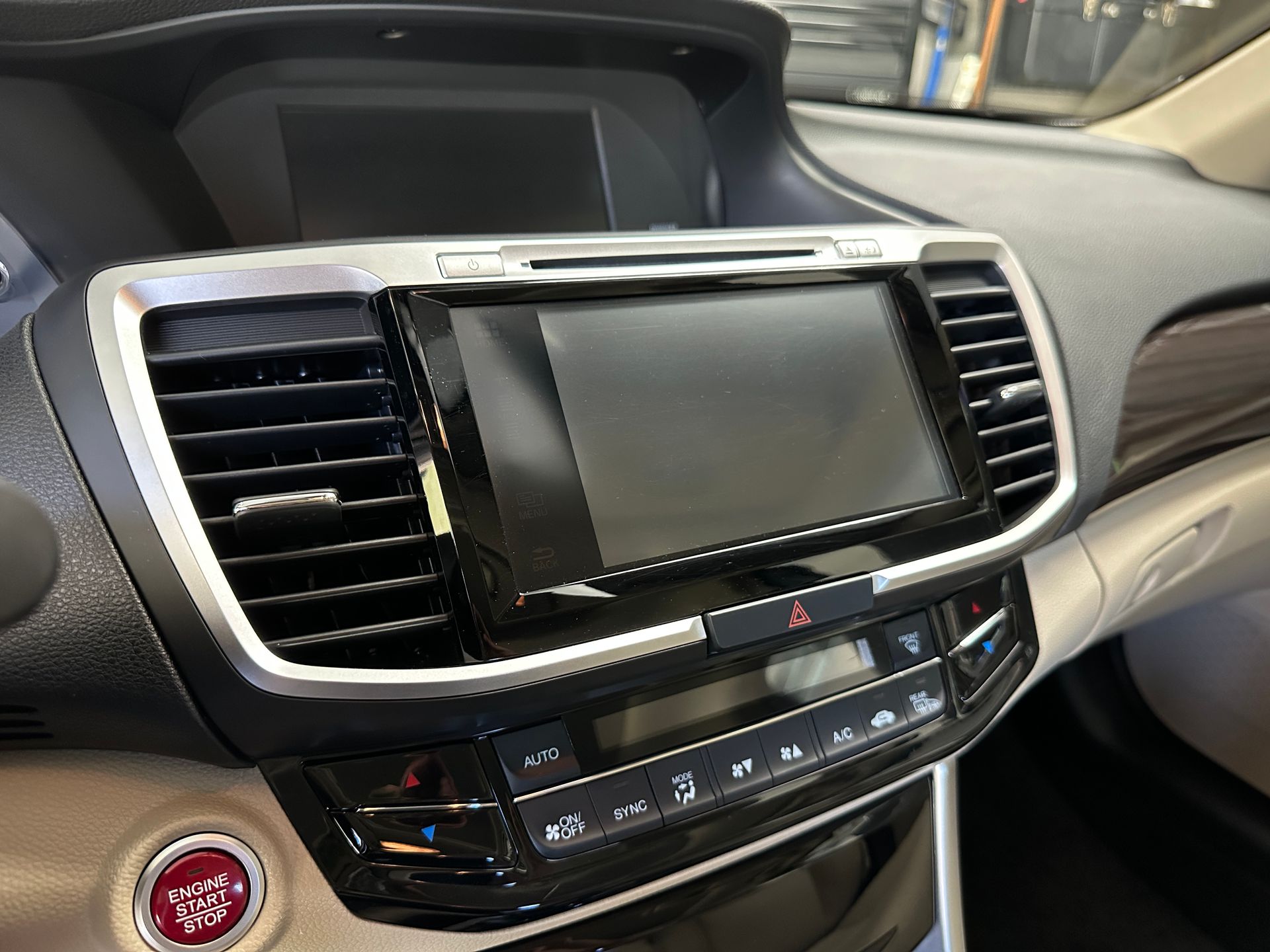 Car dashboard with infotainment screen, climate controls, and a red start button.