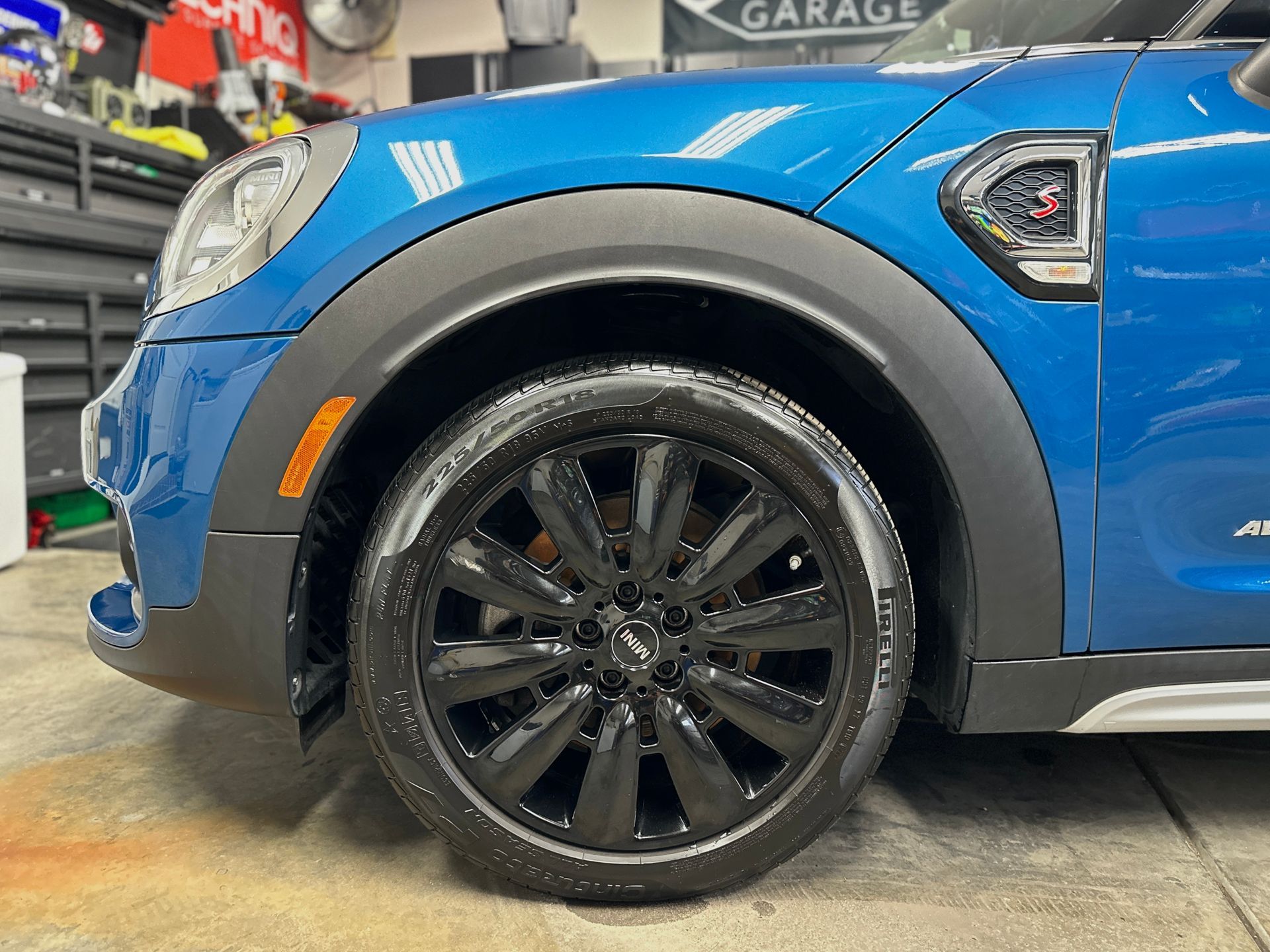 Blue Mini Cooper car tire and wheel, black rim, front quarter view.