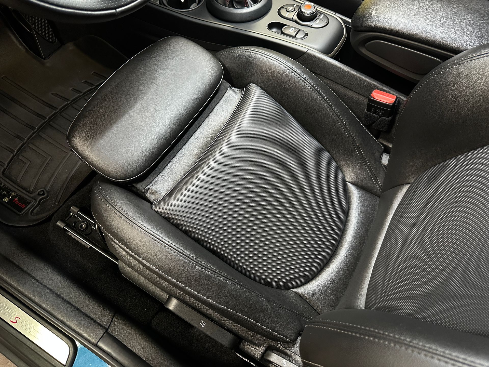 Black leather car seat with a mesh seat back and headrest, angled view.