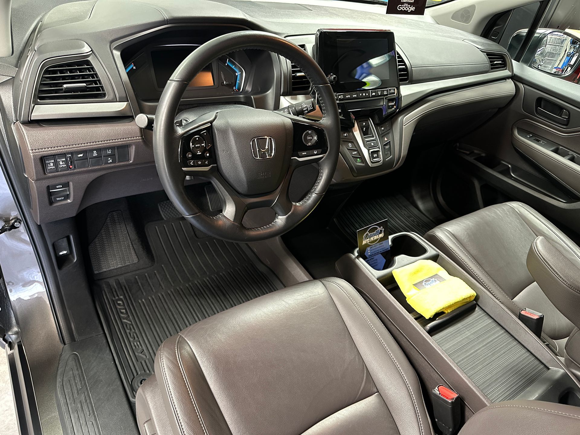 Brown leather interior of a Honda Odyssey minivan. Steering wheel, console, and dashboard are visible.