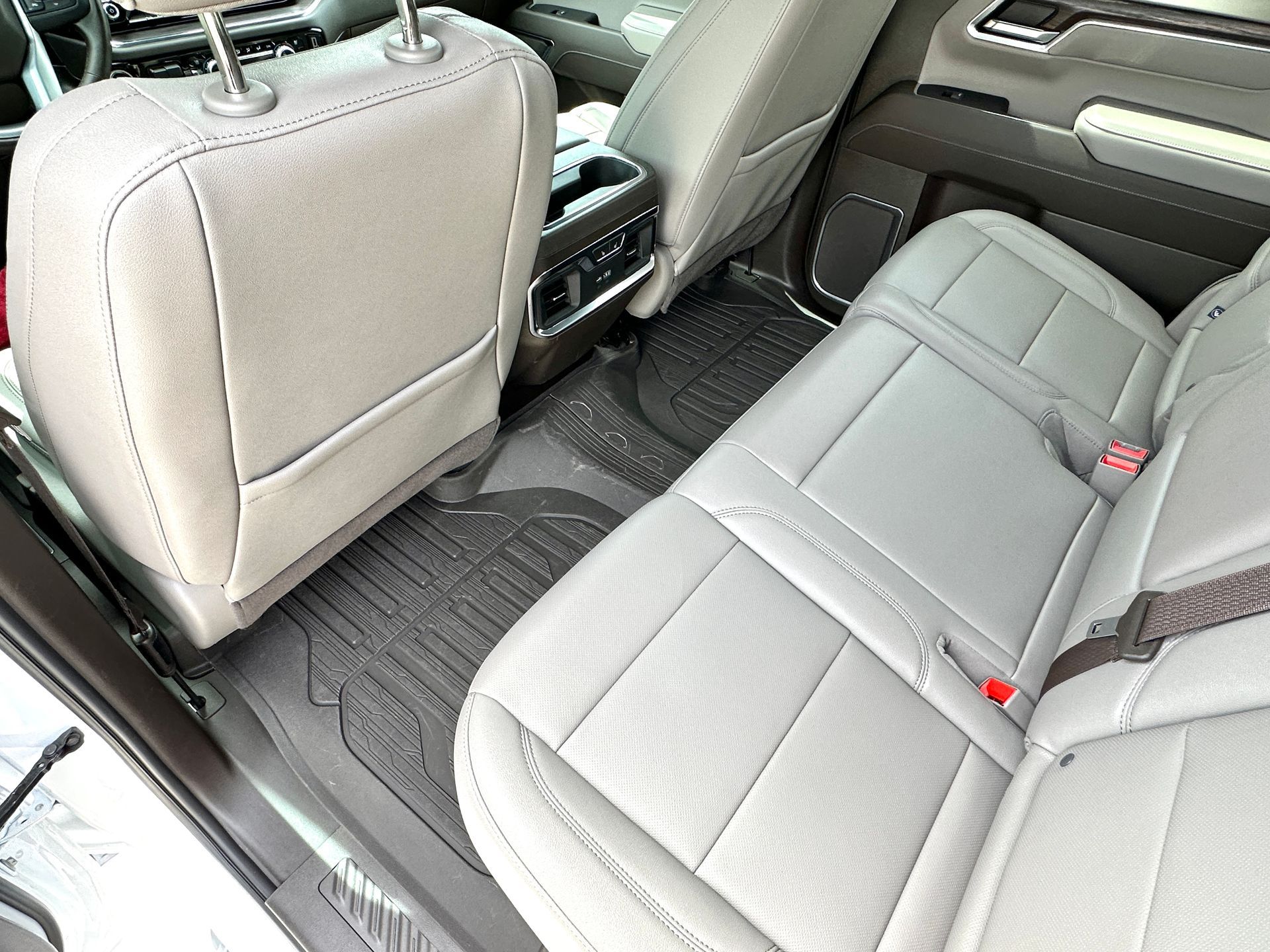 Gray leather truck backseat with black rubber floor mats.