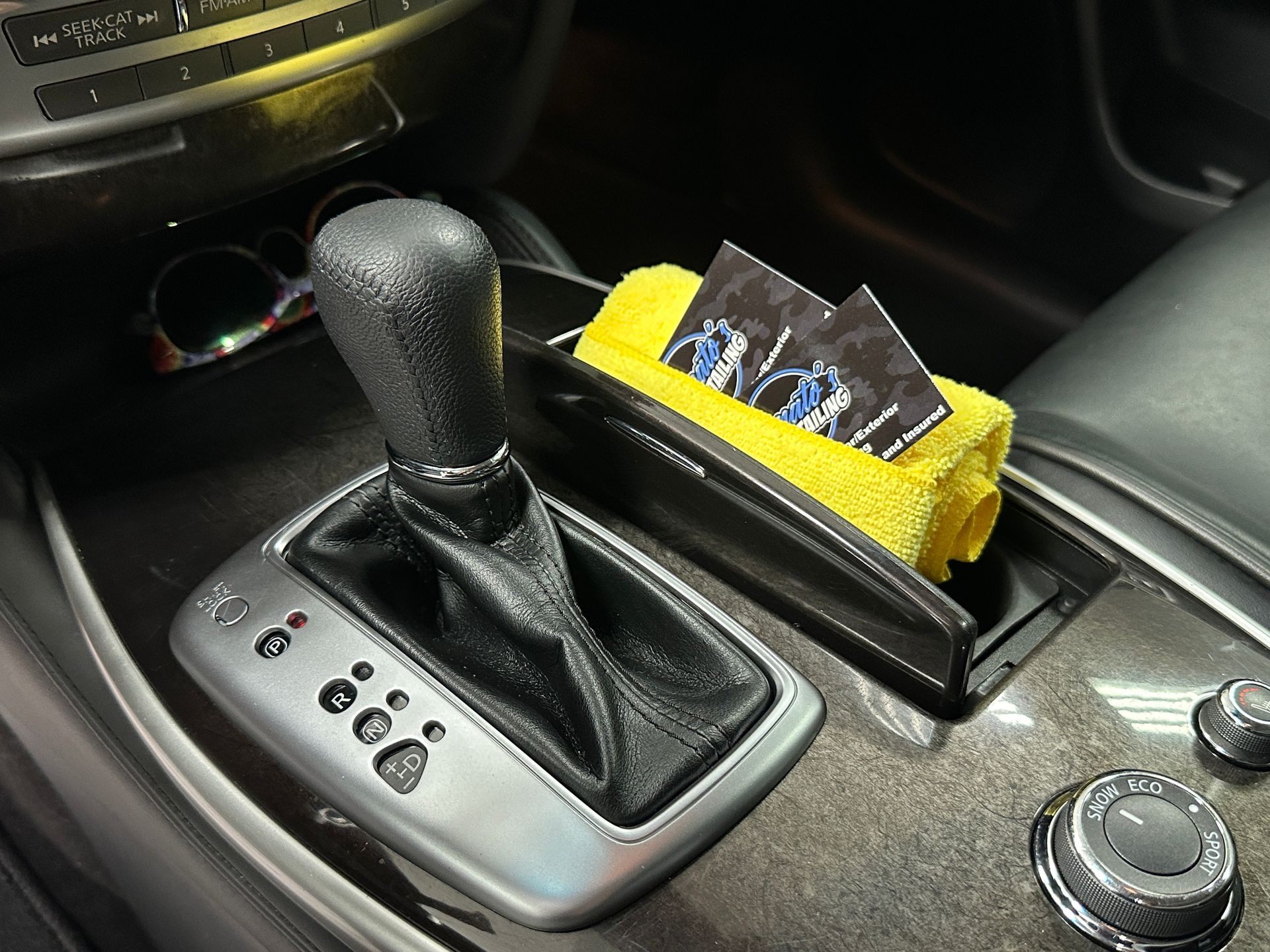 Car interior with gear shift, business cards, and yellow cloth in console.