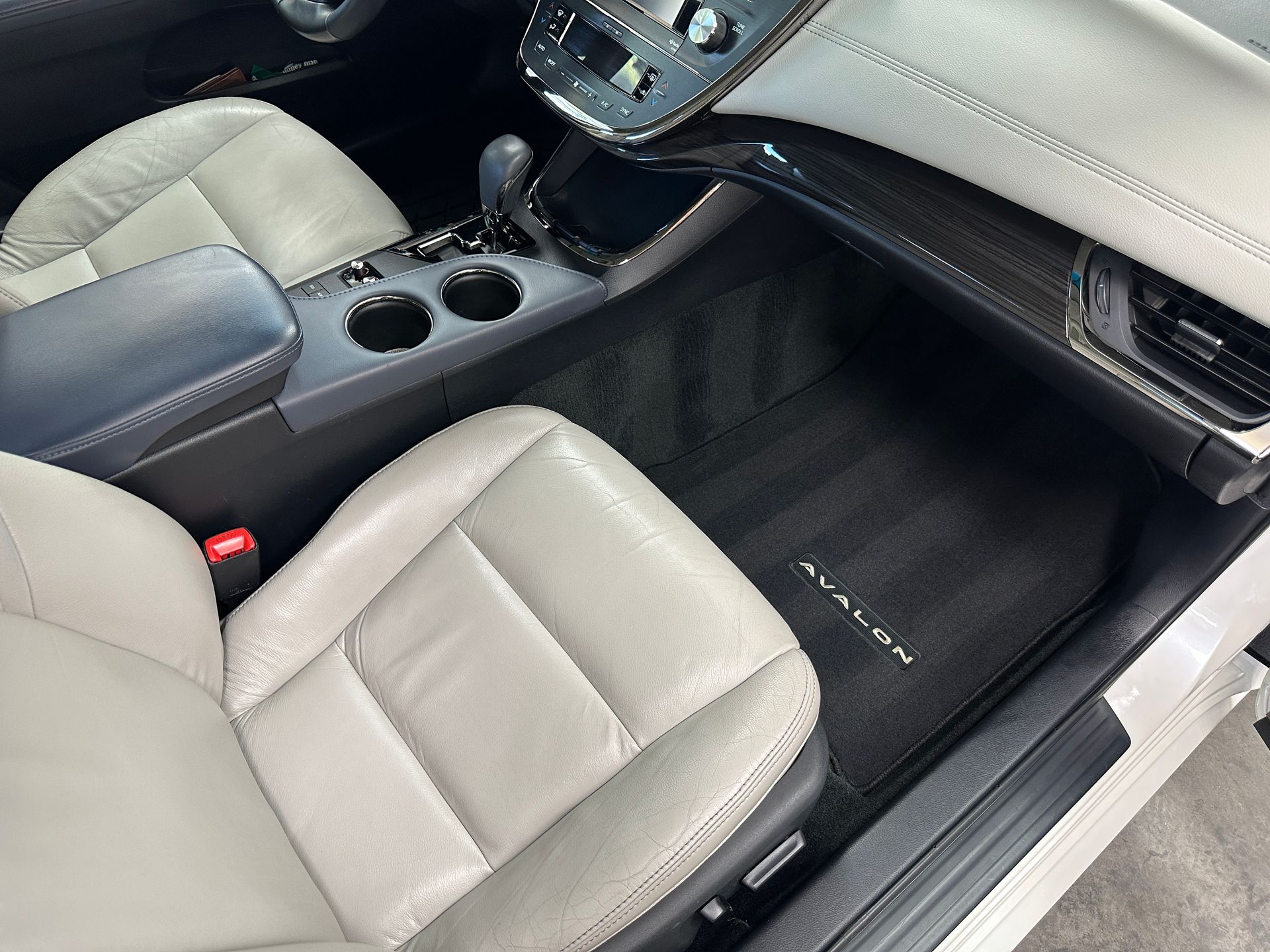Beige leather car interior, including seats, dashboard, and floor mats that say 