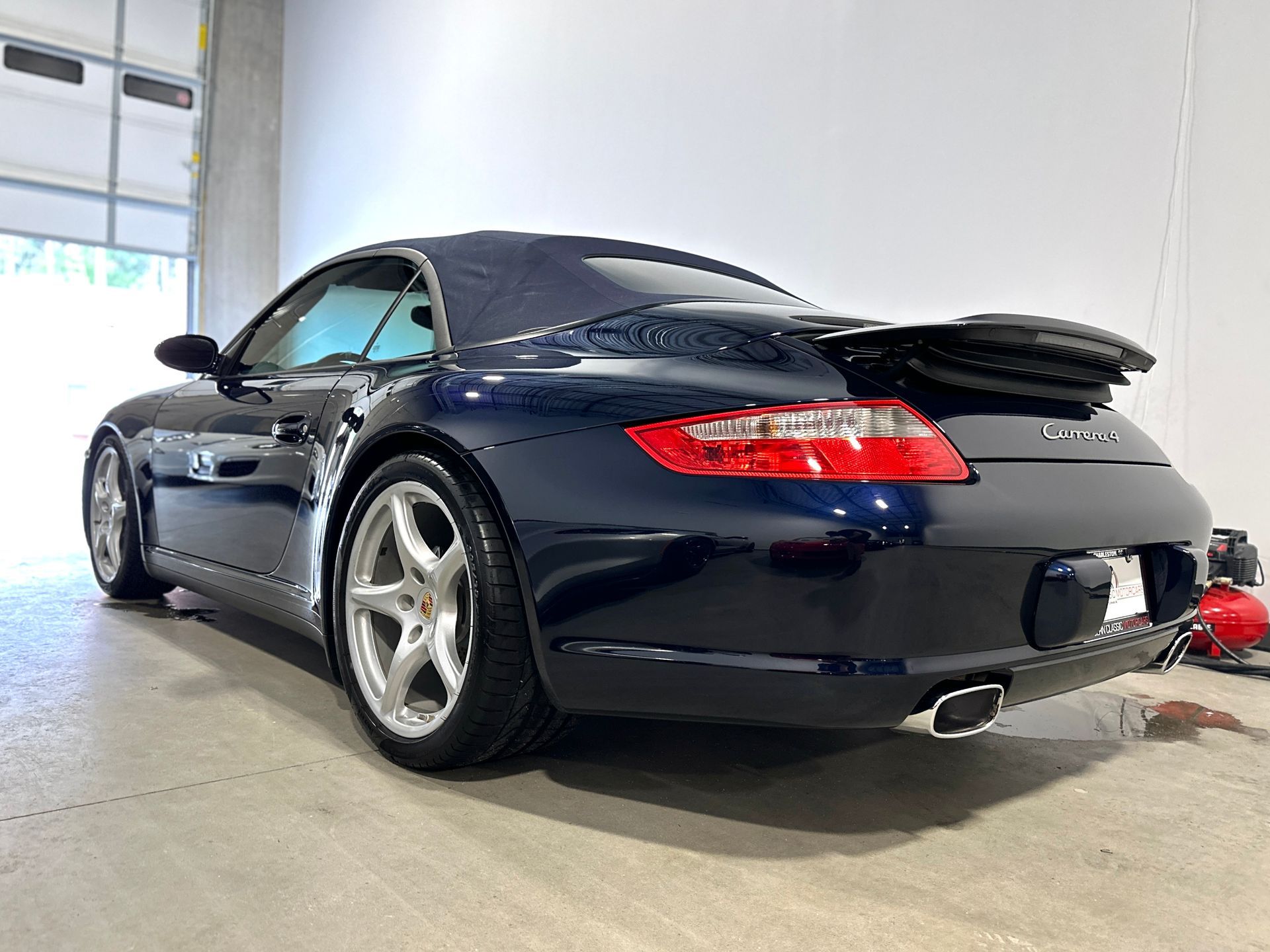 Dark blue Porsche convertible parked inside a garage.