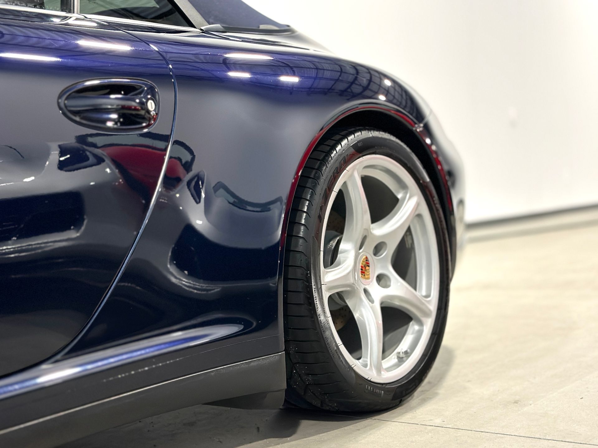 Blue Porsche sports car, close-up of a silver wheel and side panel.