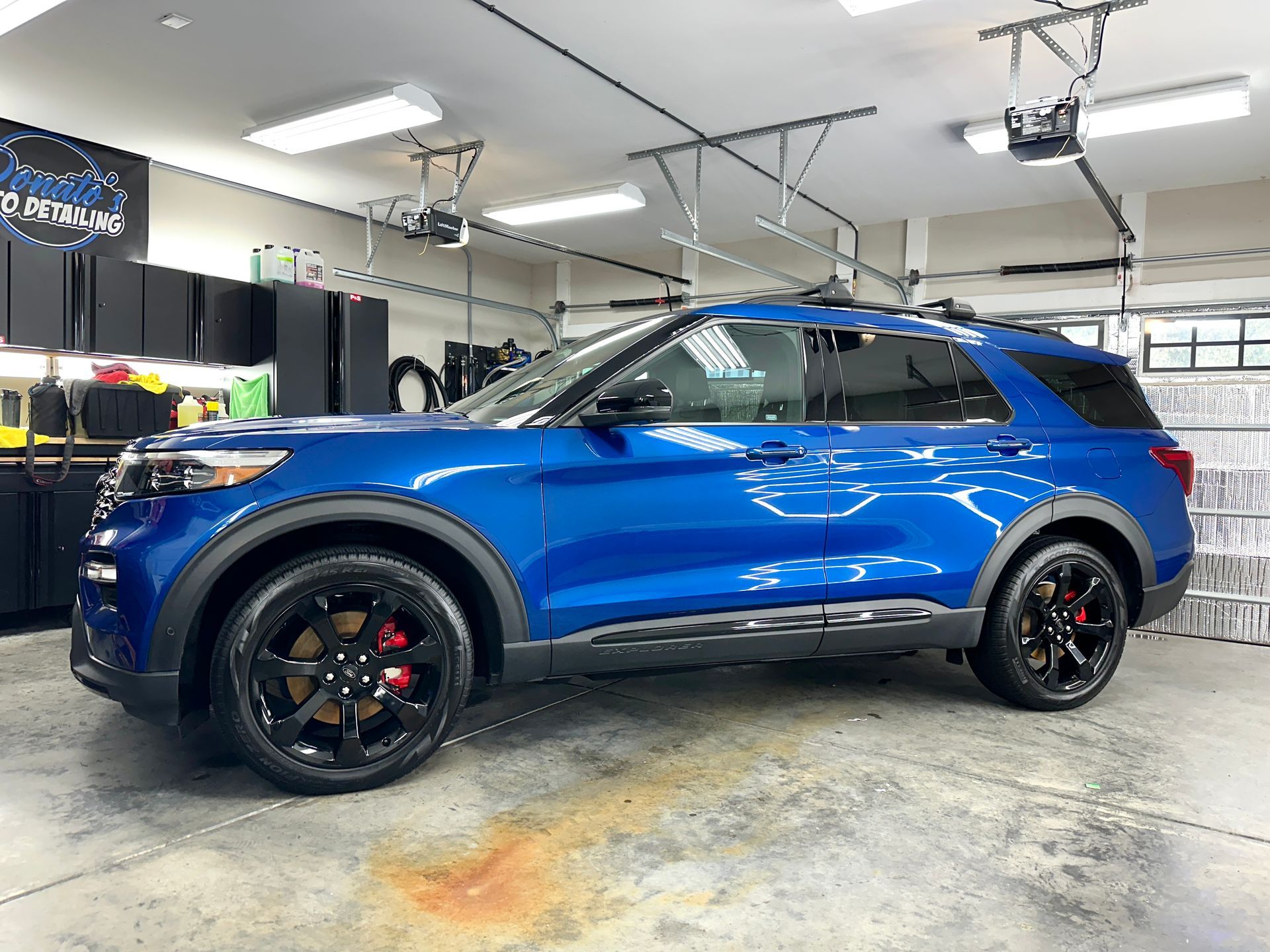 Blue Ford Explorer SUV with black wheels in a garage.