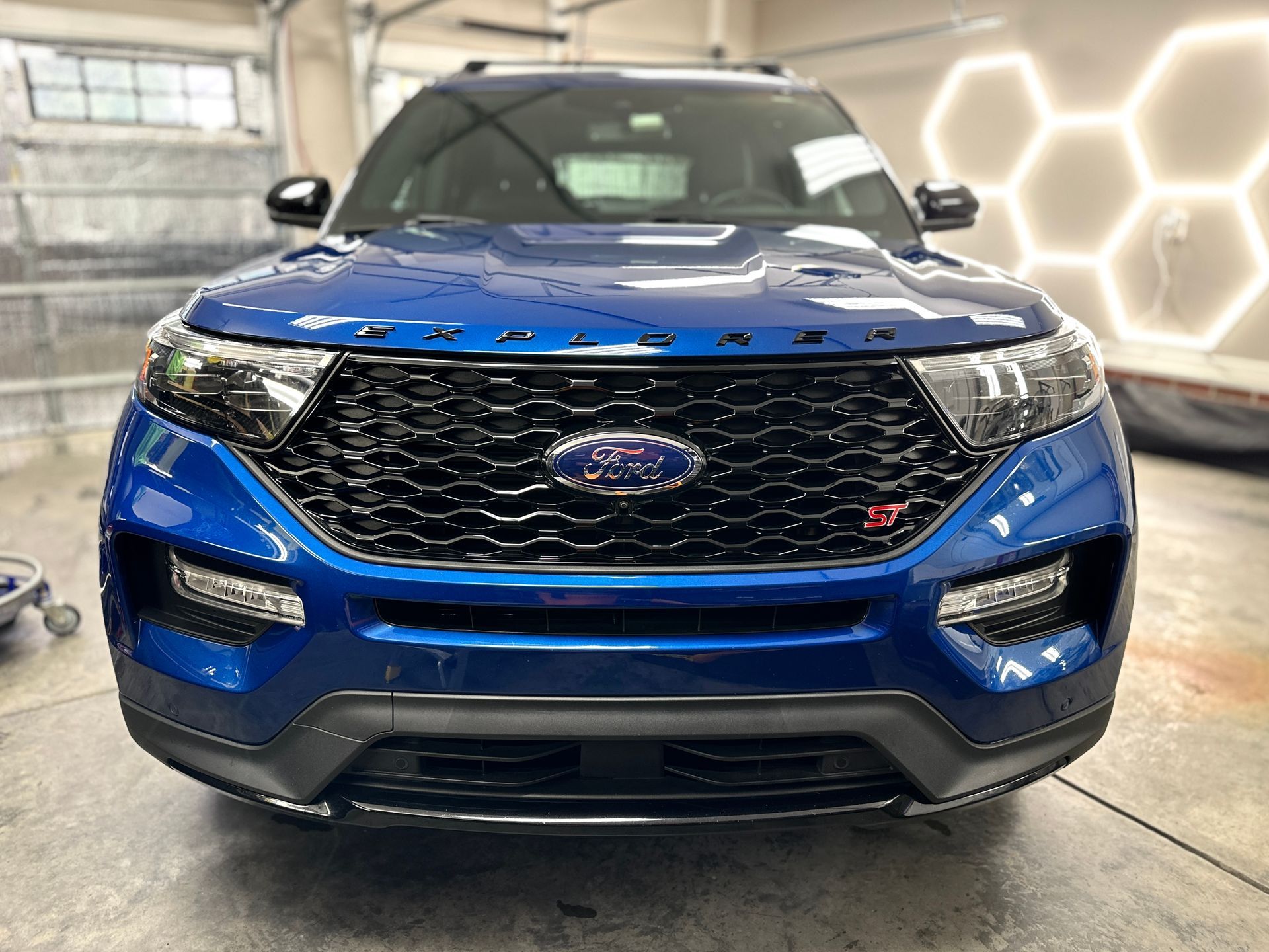 Blue Ford Explorer SUV with black accents, front view. Ford logo on grille, 