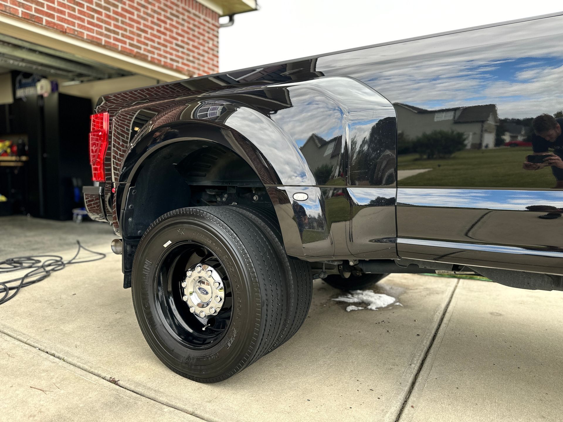 Black pickup truck with dual rear wheels parked on a driveway.