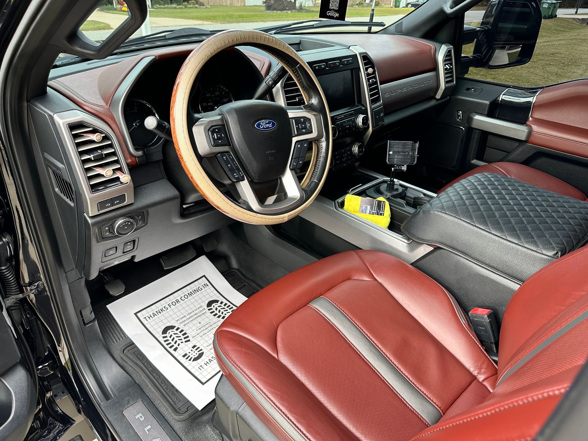 Interior of a truck with red leather seats, a tan steering wheel, and a black dashboard.