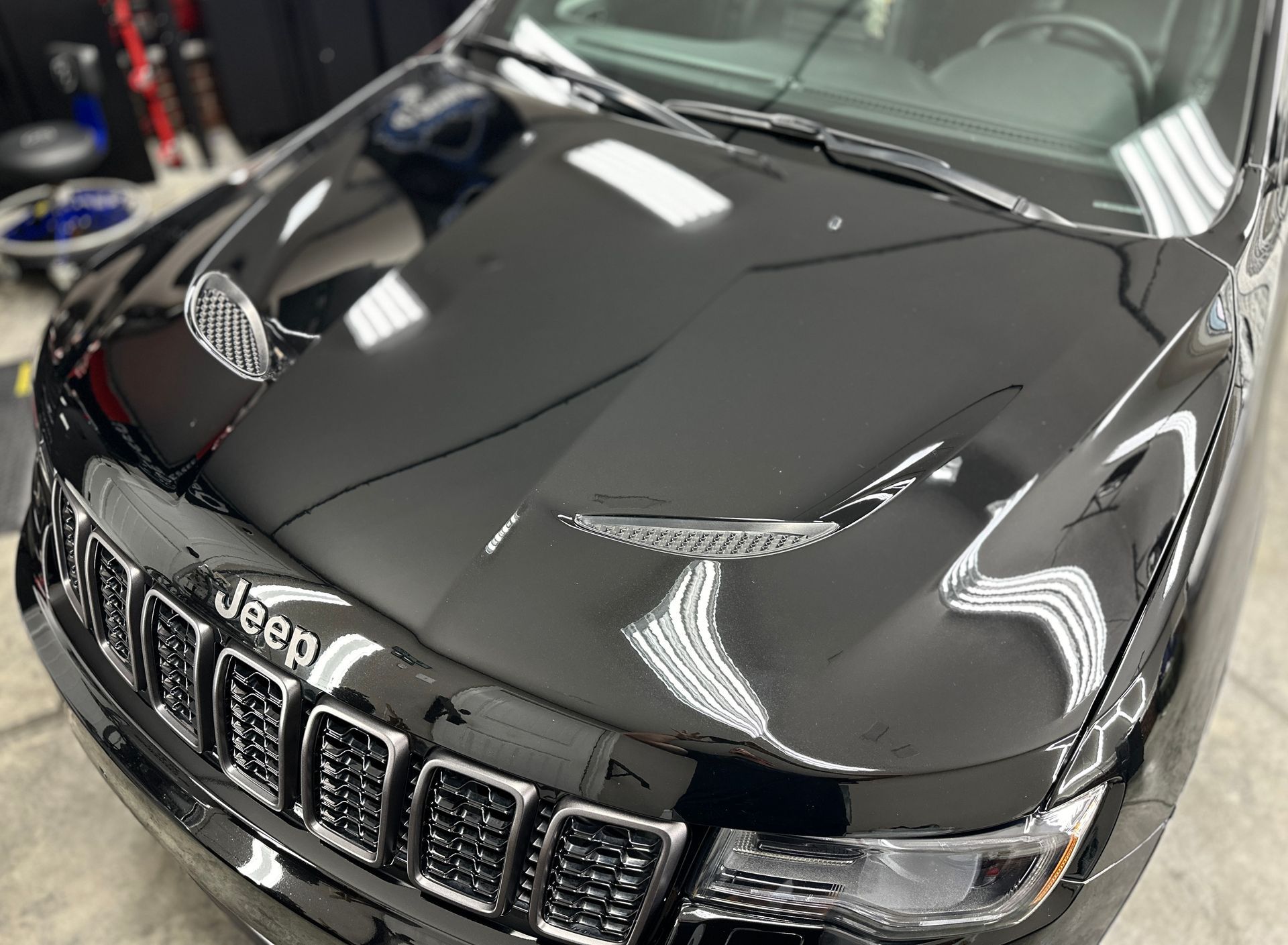 Black Jeep Grand Cherokee hood gleaming under bright lights.
