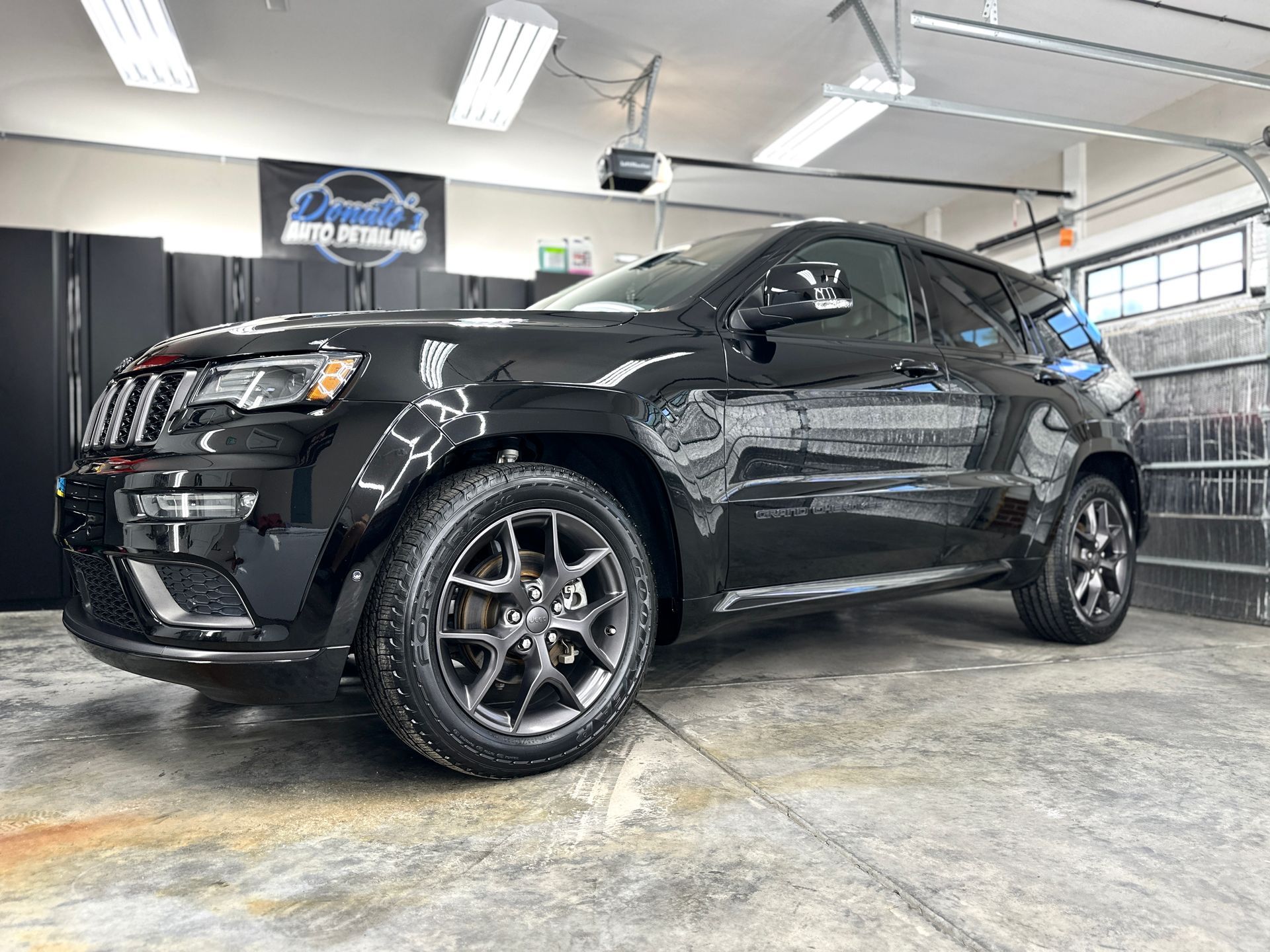 Black Jeep Grand Cherokee SUV parked inside a garage.