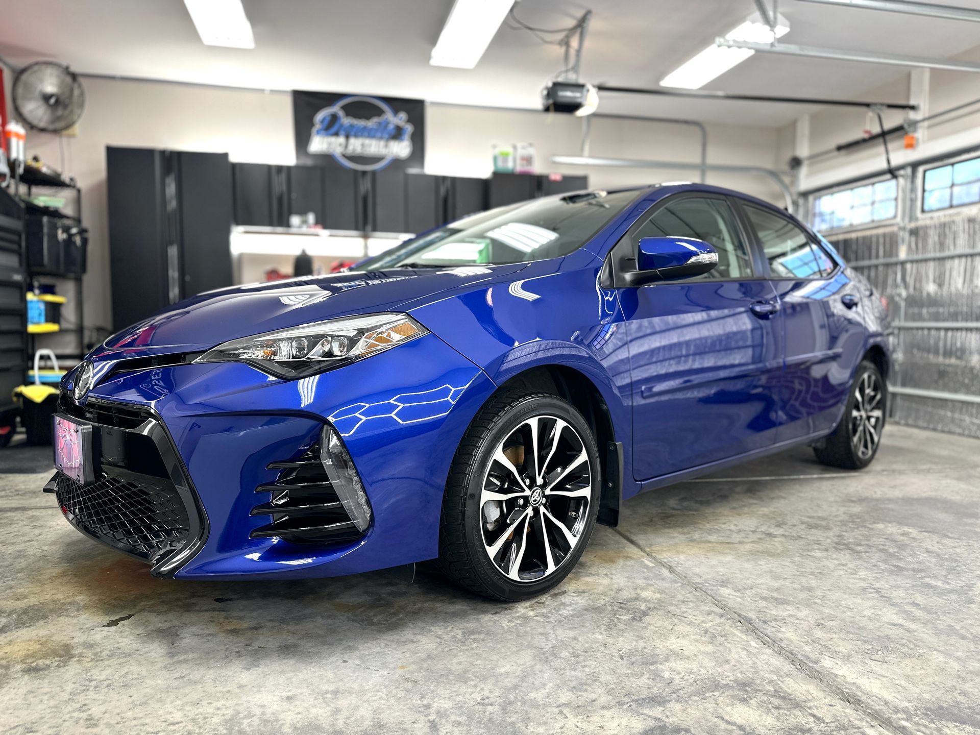Blue Toyota Corolla parked in a well-lit garage, with black trim and black wheels, detailed car.