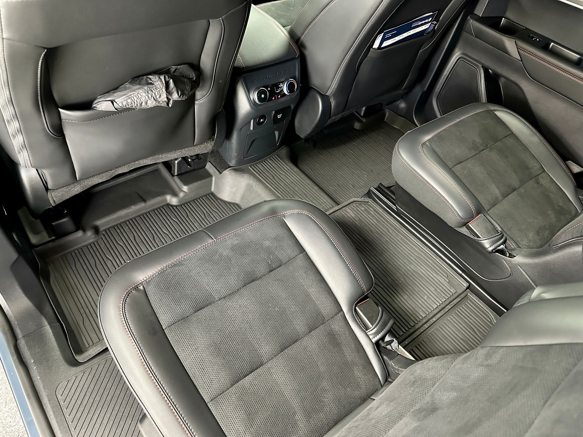 Interior of a black car with two second-row captain's chairs and black rubber floor mats.