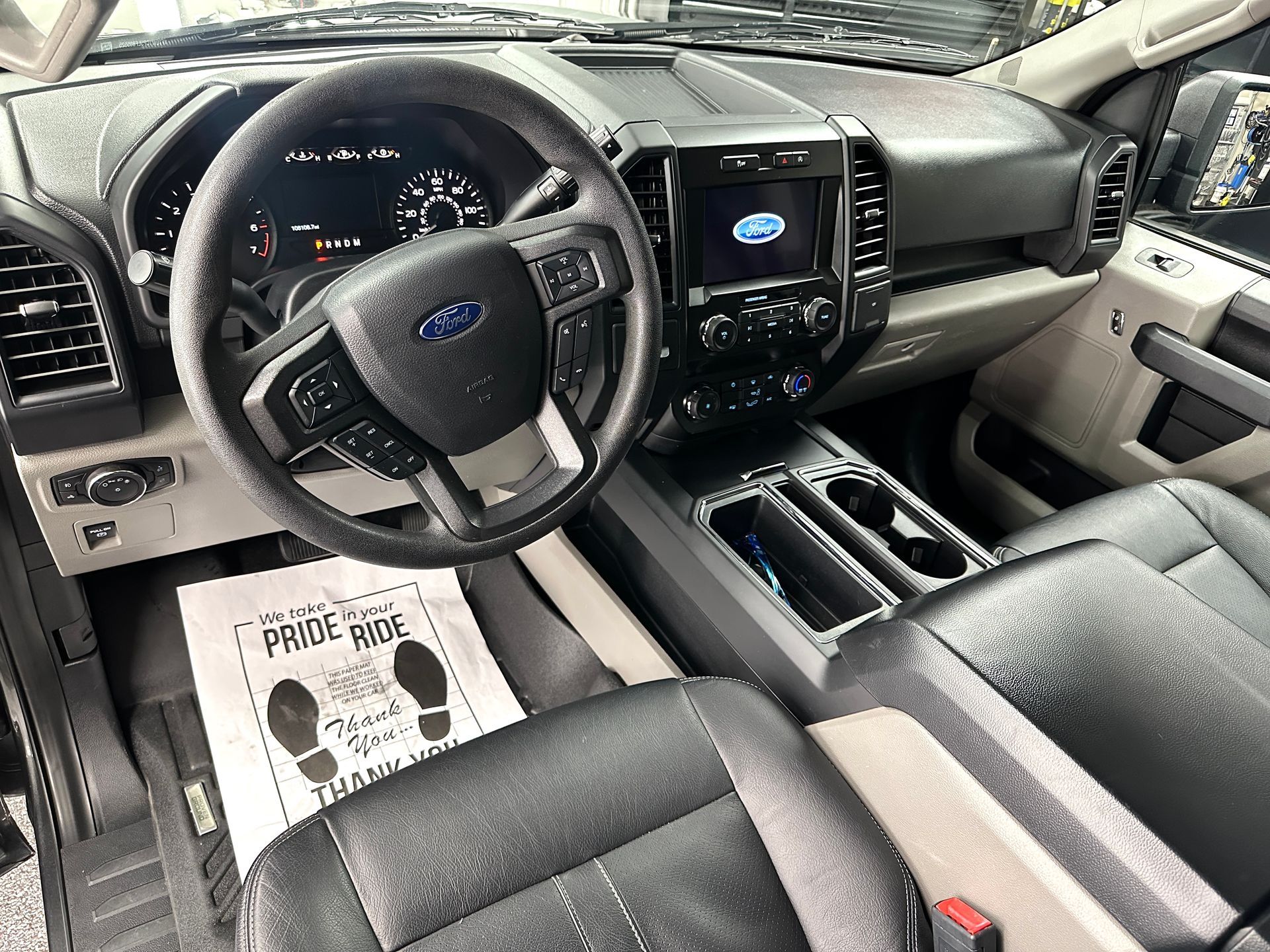 Interior of a black Ford pickup truck. Steering wheel, dashboard, center console, and seats visible.