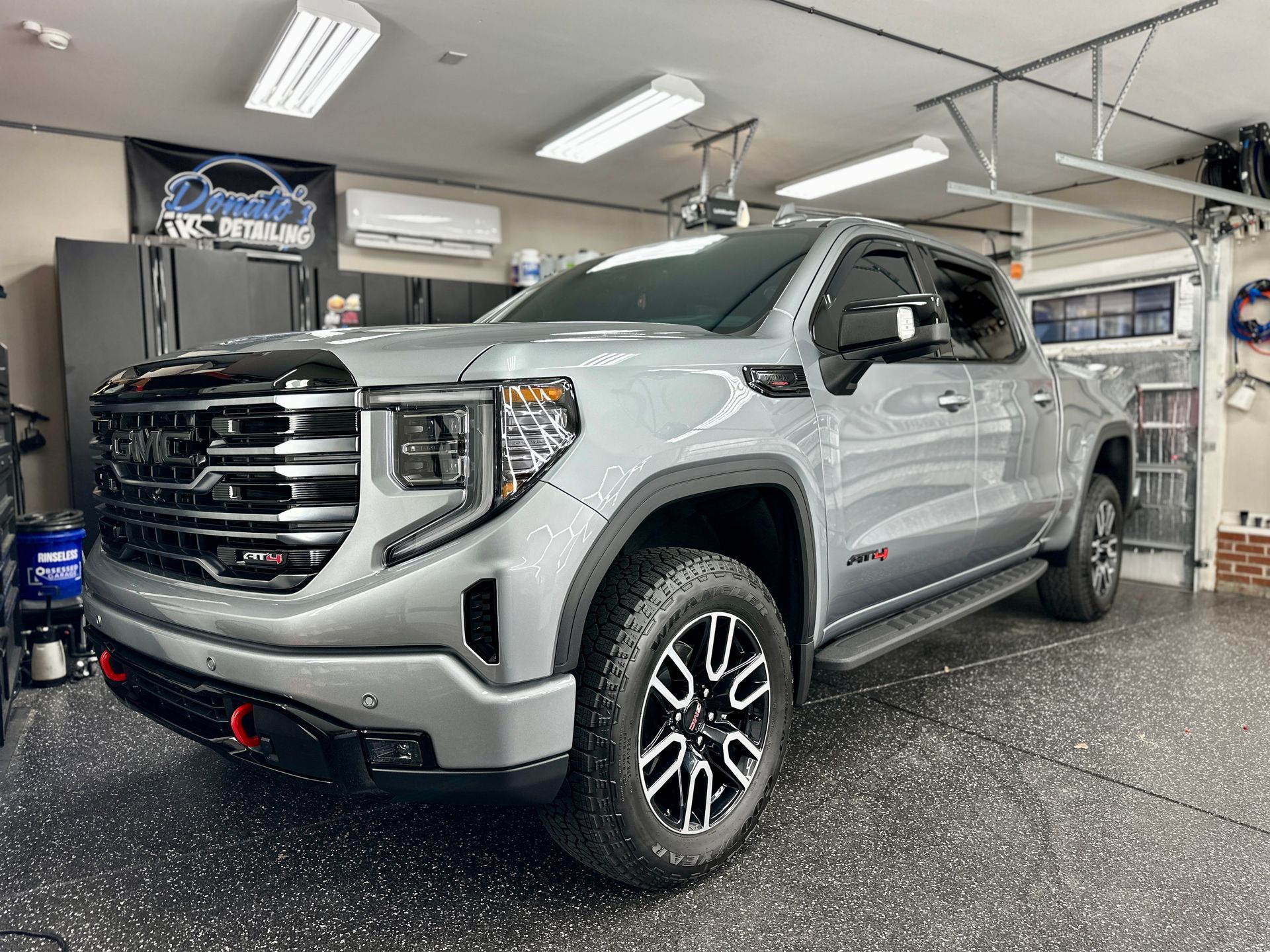 Gray GMC Sierra truck parked in a well-lit garage, with black and red accents.