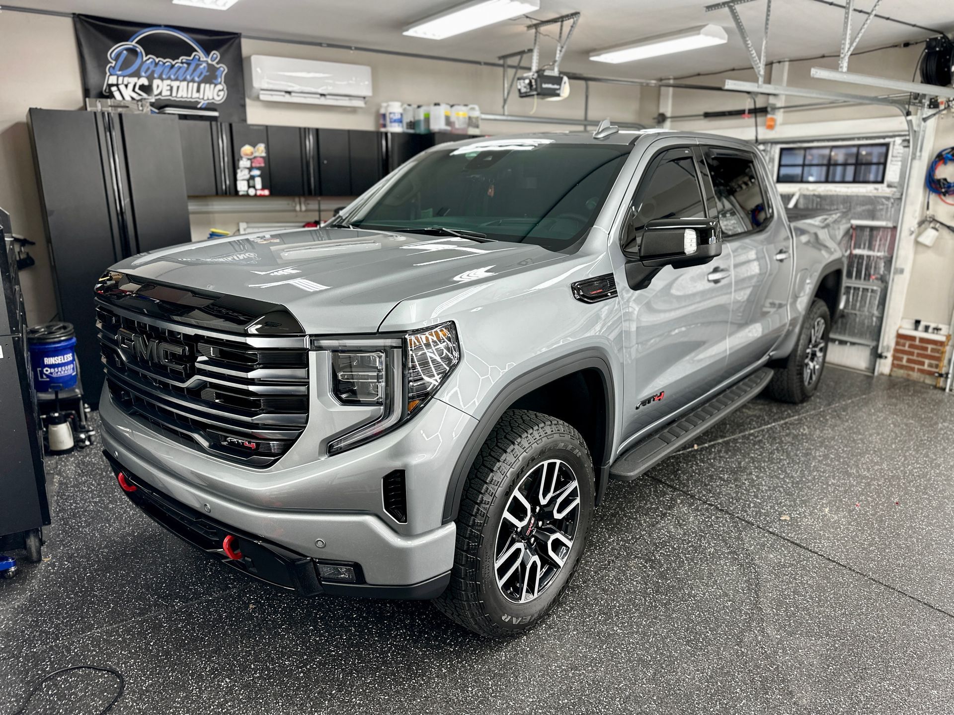 Silver GMC Sierra truck in a garage with black and gray floor.