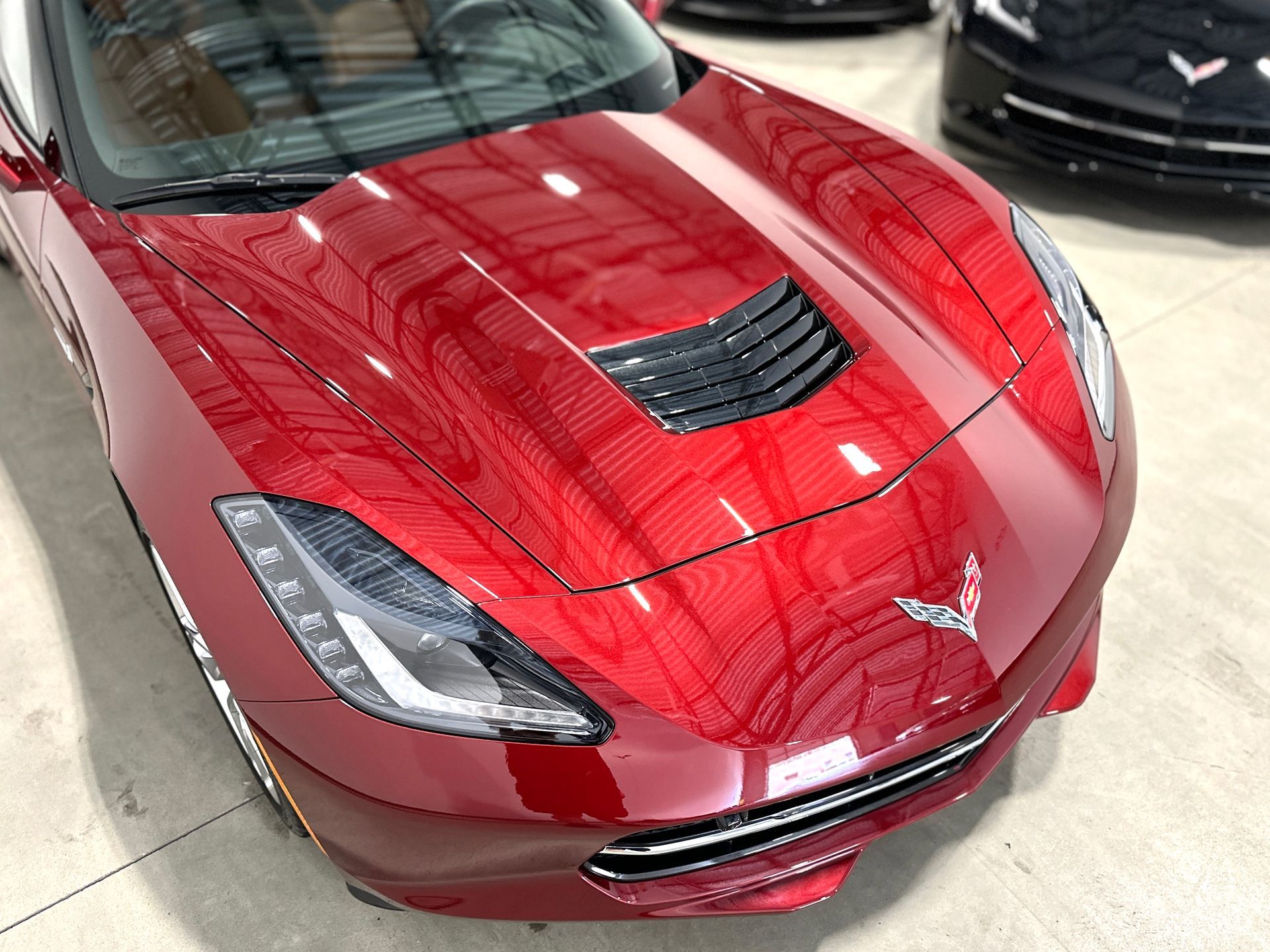 Red Corvette sports car, glossy hood, parked indoors.