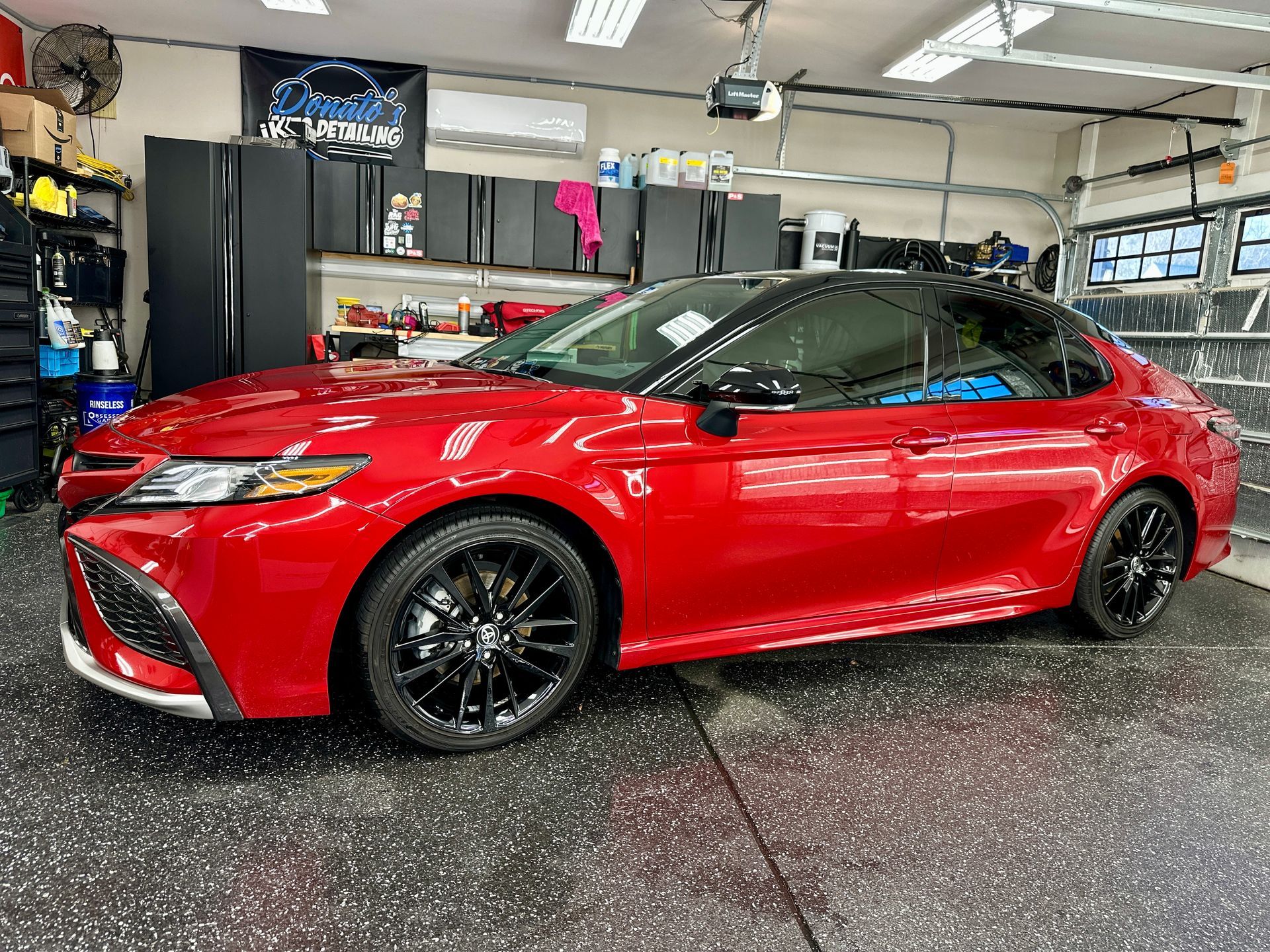 Red Toyota Camry with black roof and wheels parked in a garage.