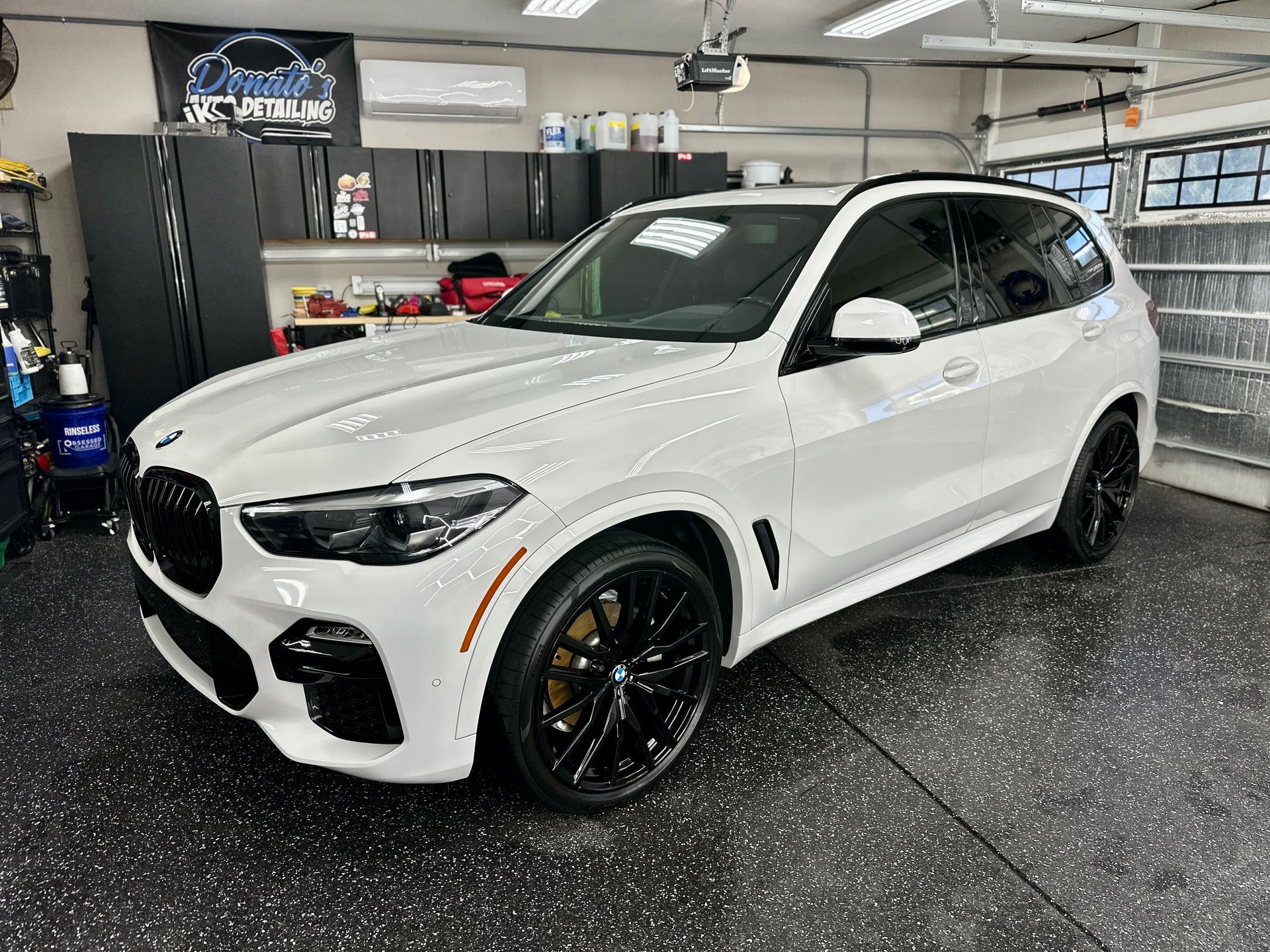 White BMW SUV parked in a garage with black detailing and wheels.