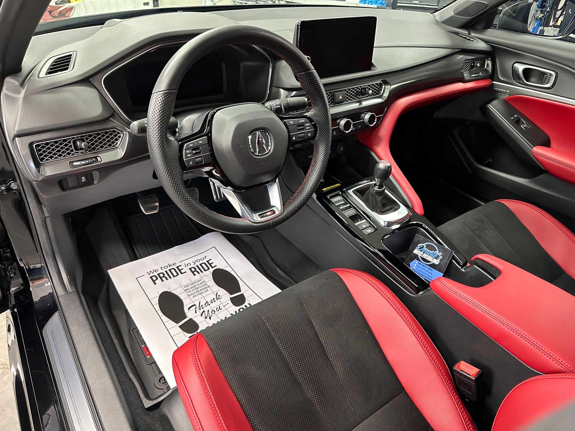 Black and red car interior with steering wheel, dashboard, seats, and a 