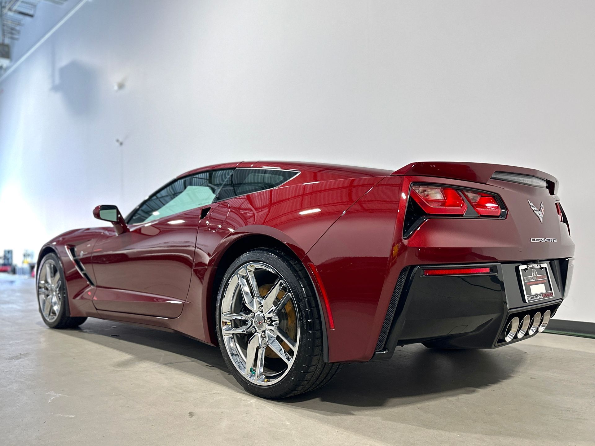Red Corvette sports car on display, shiny wheels and rear angled view.