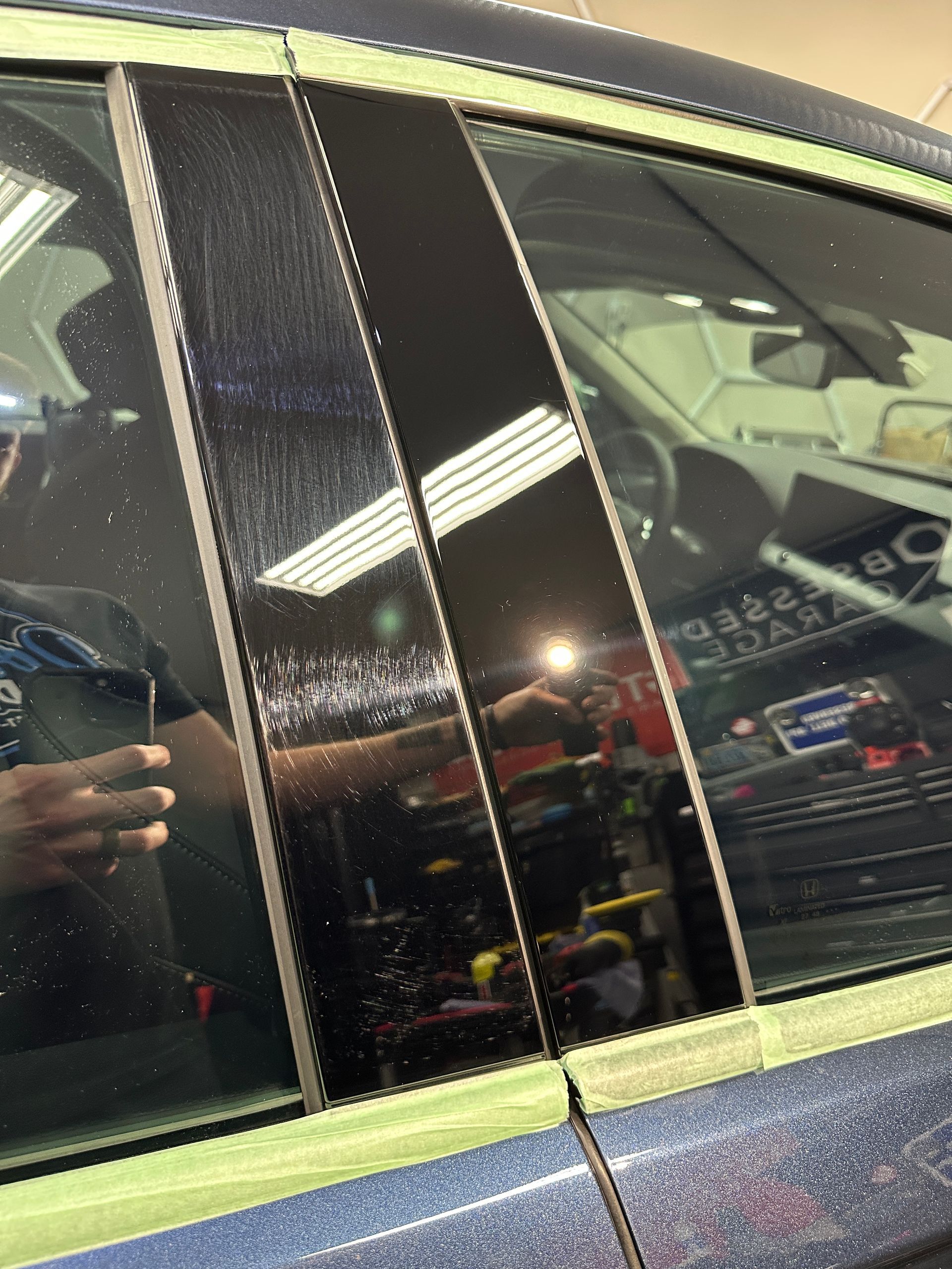 Black car door pillars, one polished and glossy, the other with scratches, taped for detailing.