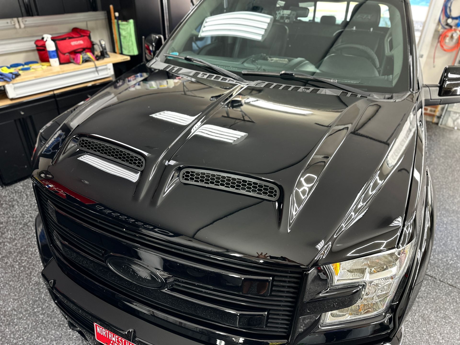 Black pickup truck hood with two vents in a garage.