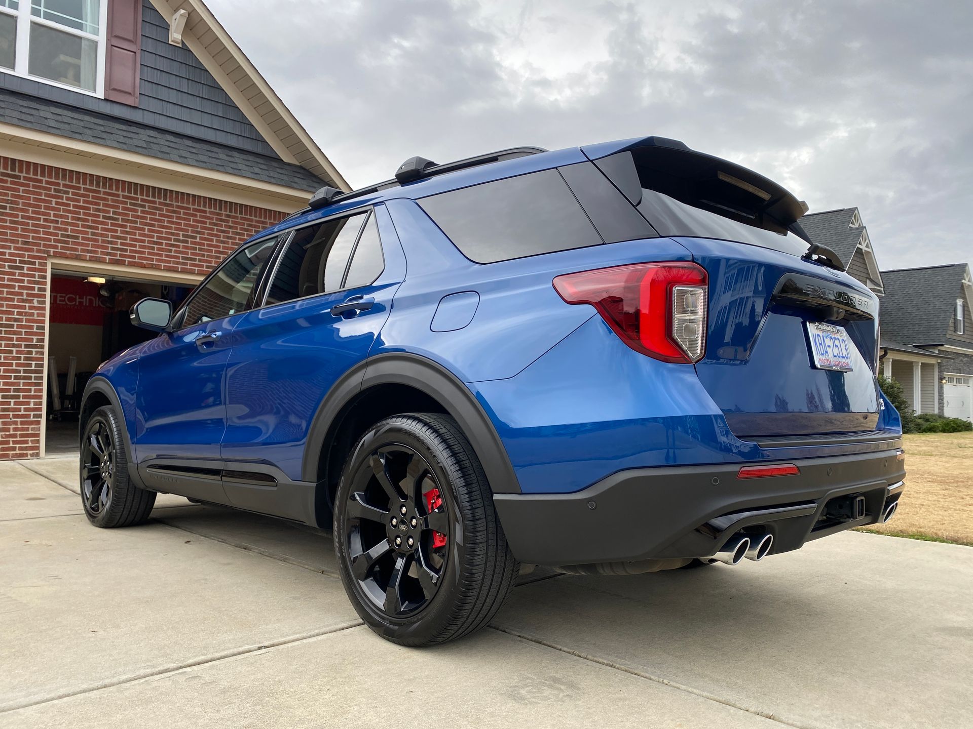 Blue Ford Explorer SUV parked on a driveway with black wheels and red brake calipers.