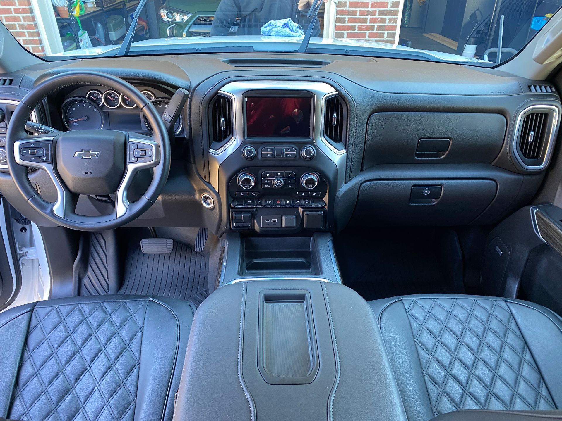 Interior of a Chevrolet truck. Black and silver dashboard, steering wheel, and seats. Center console and infotainment screen.