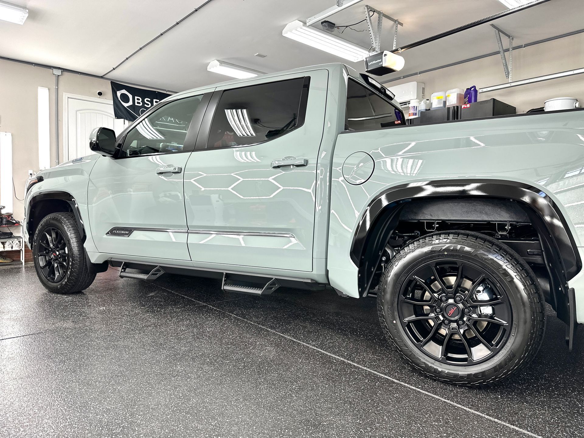 Green Toyota Tundra pickup truck with black wheels parked indoors.