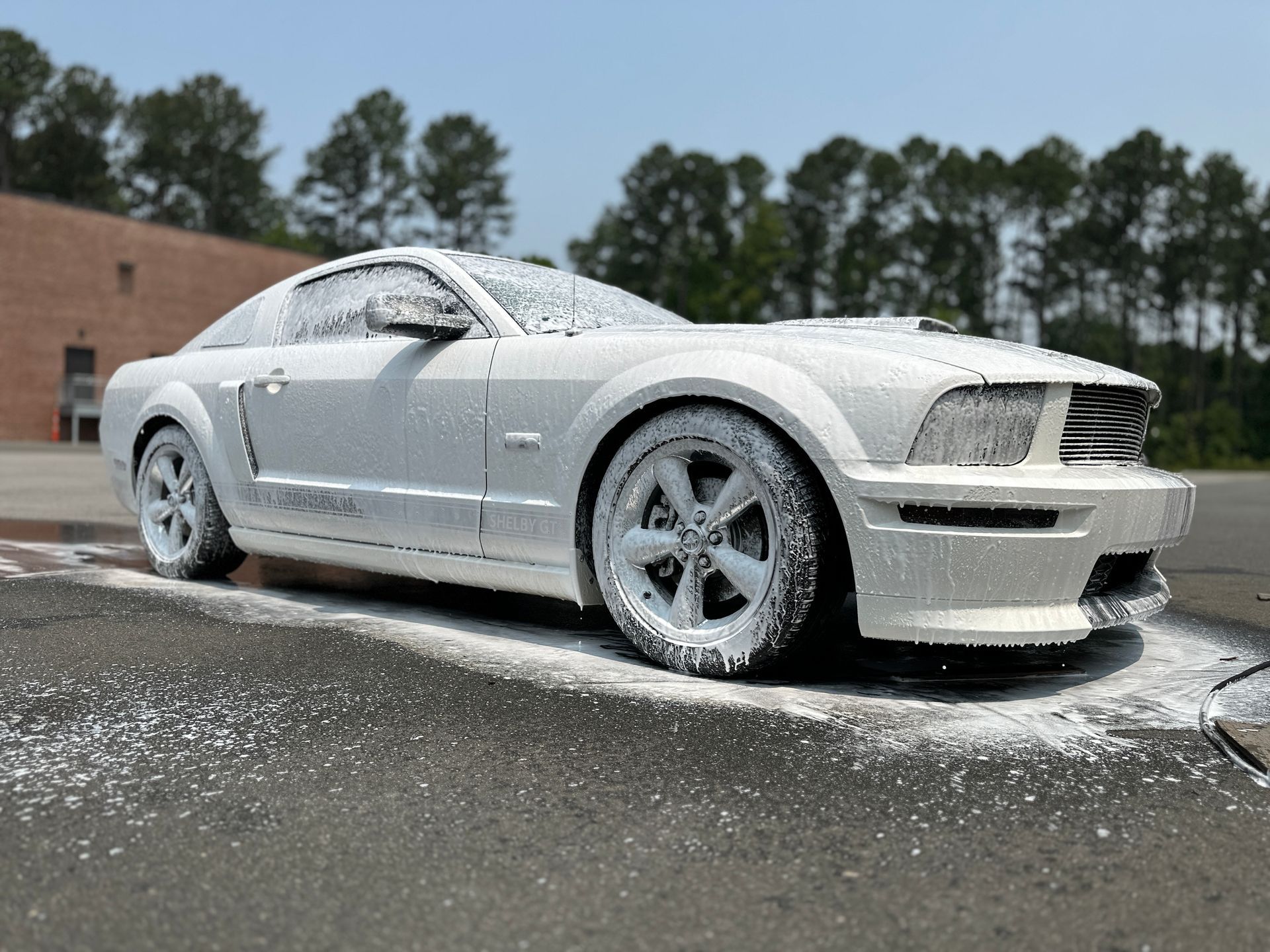 White Mustang covered in white foam, parked outdoors.
