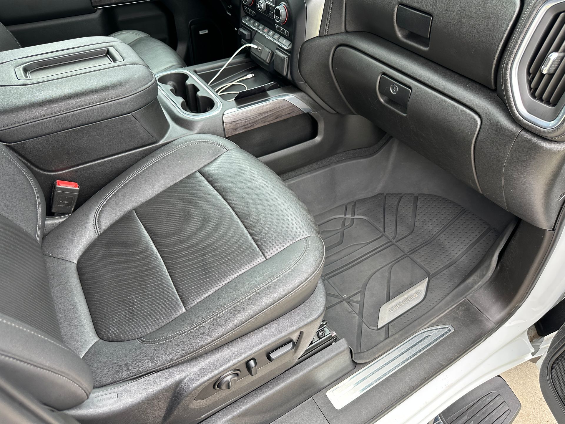Black leather truck interior with a floor mat and cup holders.