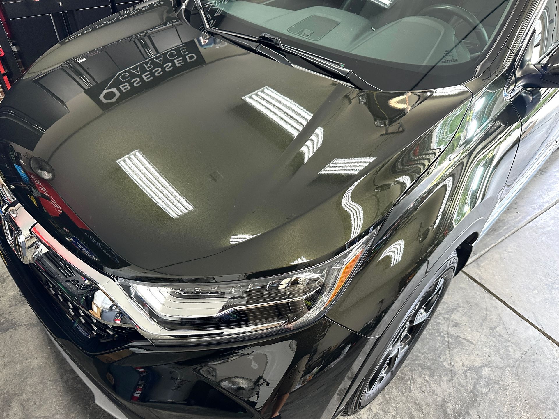Black SUV with shiny finish reflecting overhead lights.