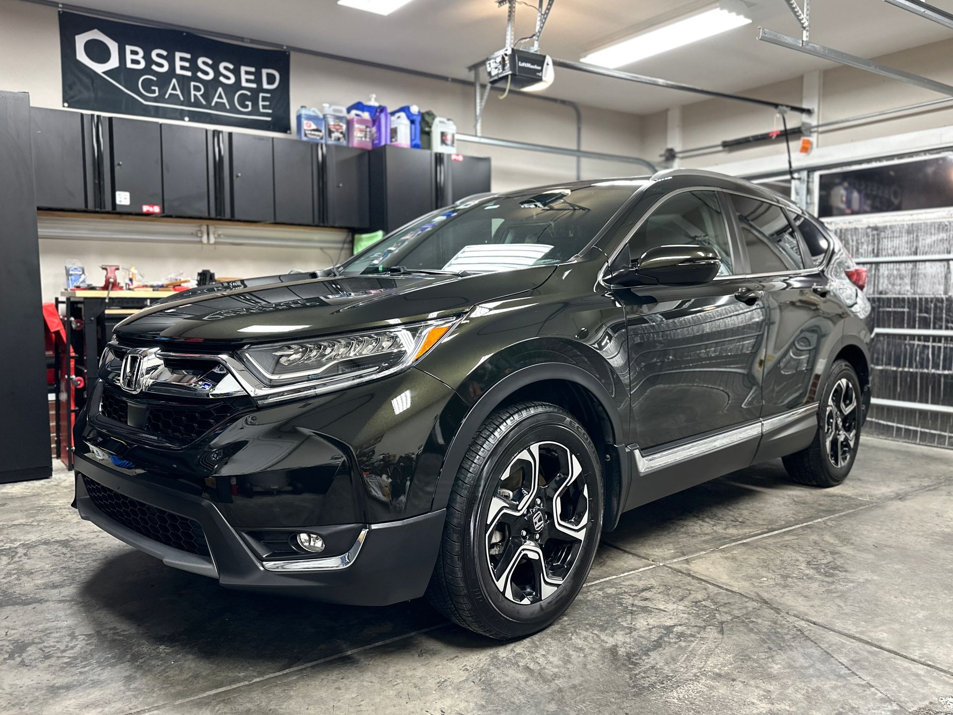 Dark green Honda CR-V in a garage, shiny with black wheels, under the 