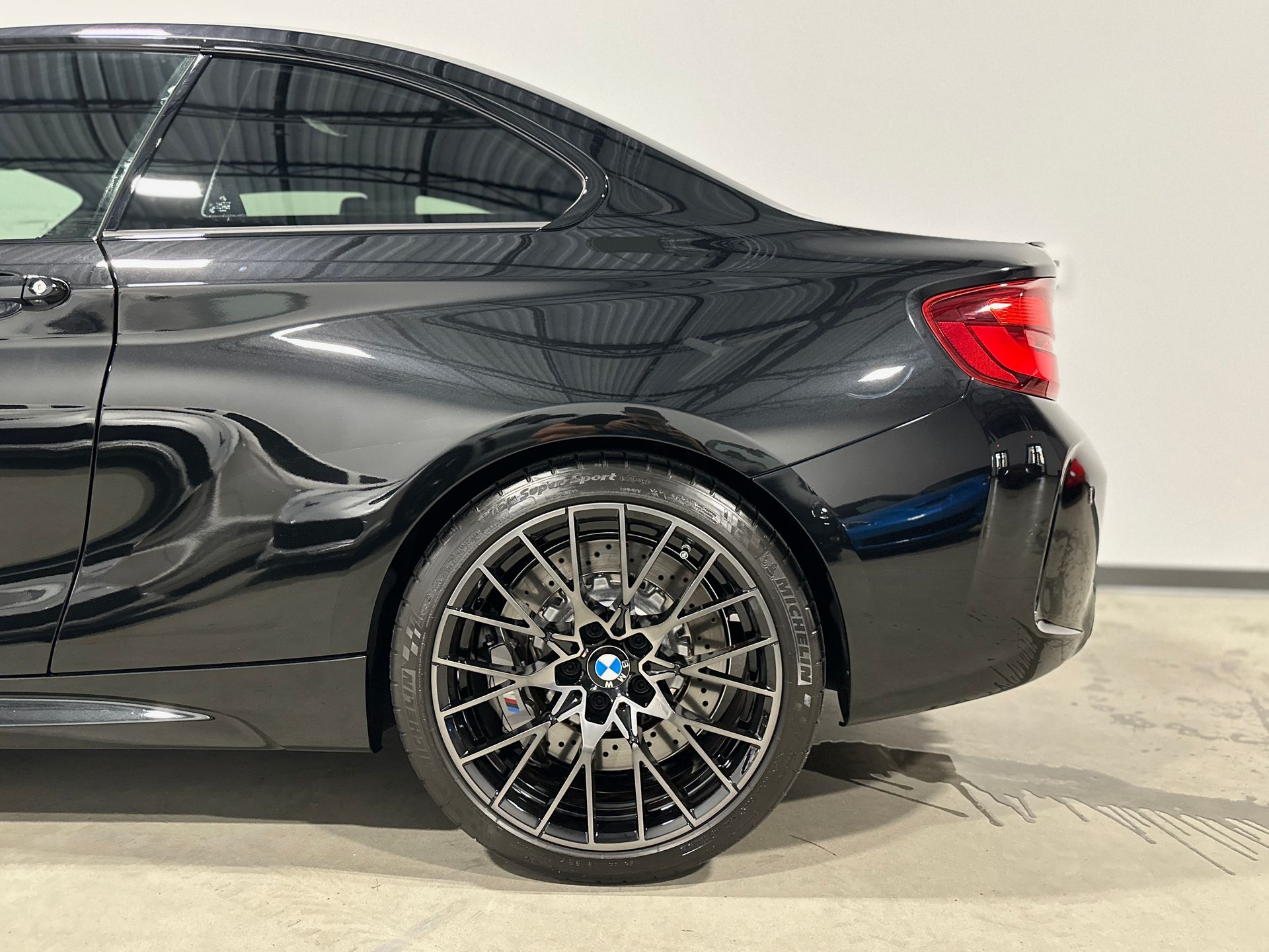 Black BMW coupe with a black rim and red taillight.