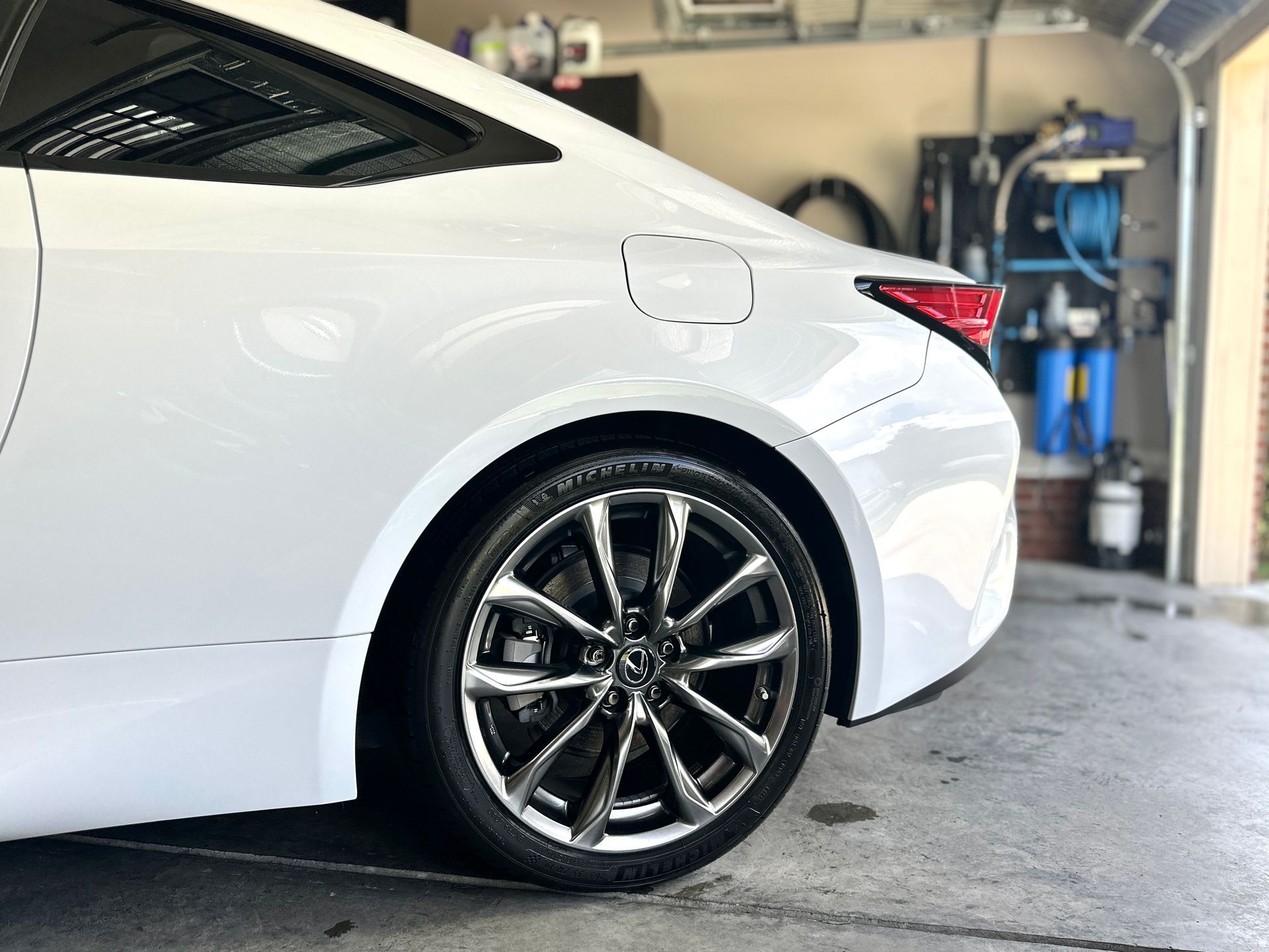 White car, rear quarter view, parked in a garage. Chrome wheels.