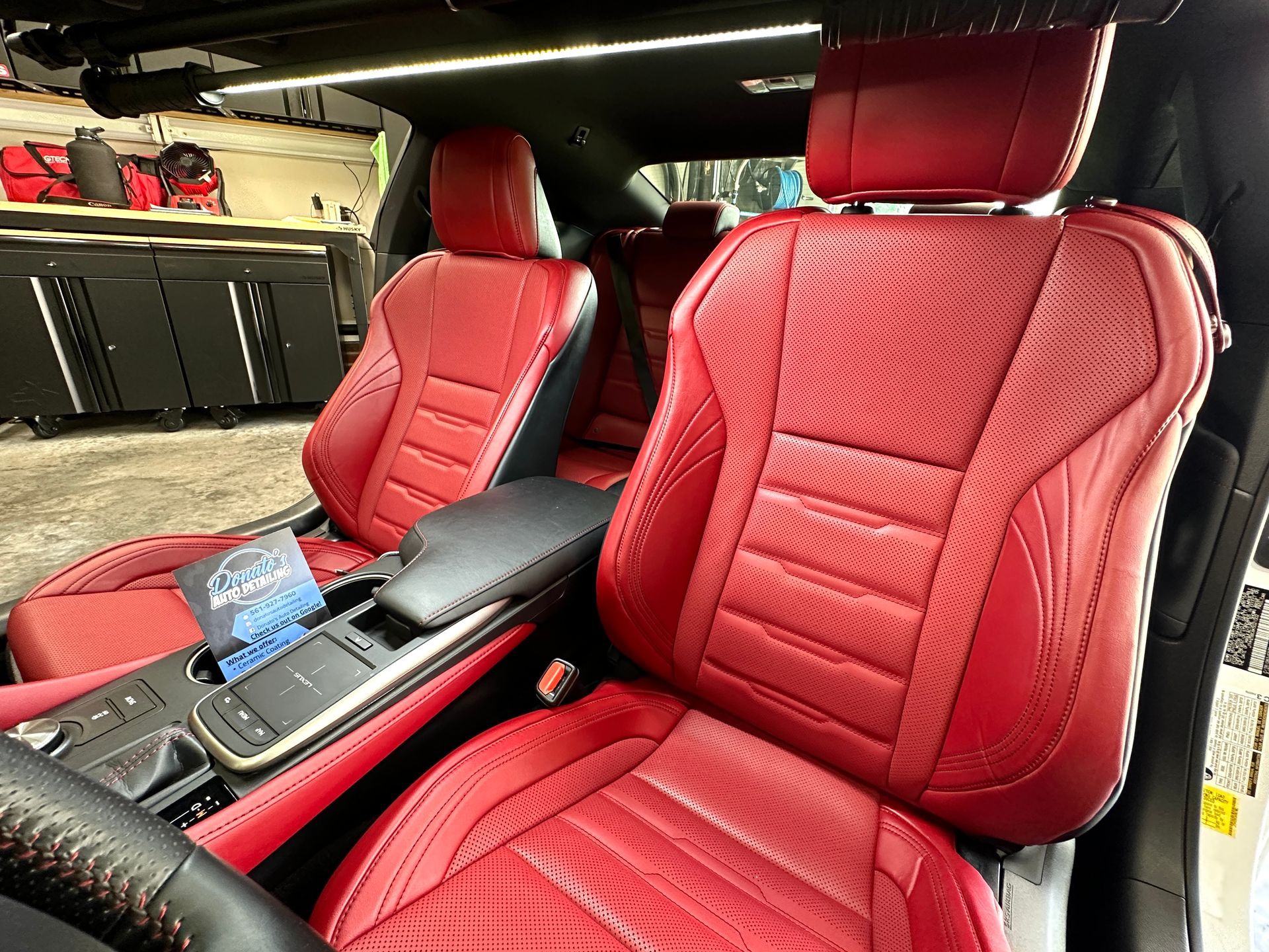 Red leather car interior with seats, armrest, and steering wheel.