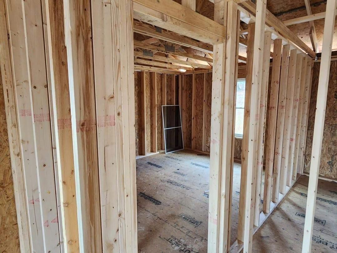 Interior of a building under construction, wooden studs forming walls and doorways.
