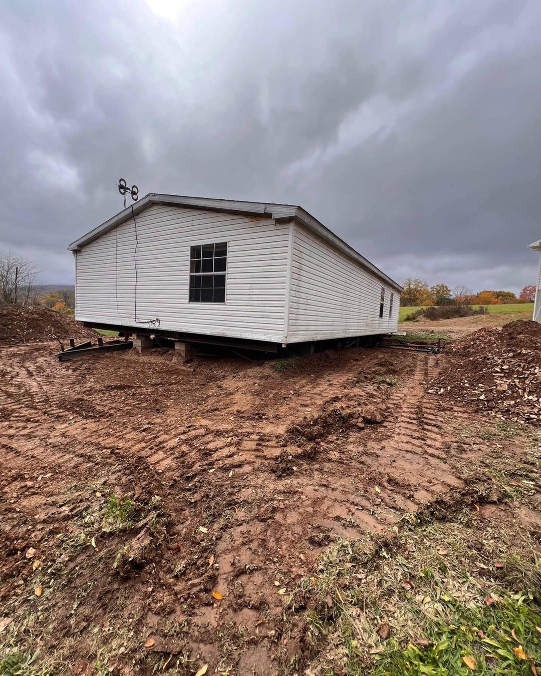 Mobile home on muddy ground under a cloudy sky.