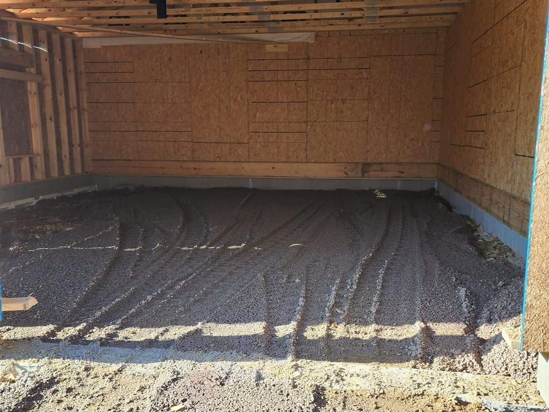 Interior of a room under construction with a gravel base; wood frame walls and ceiling.