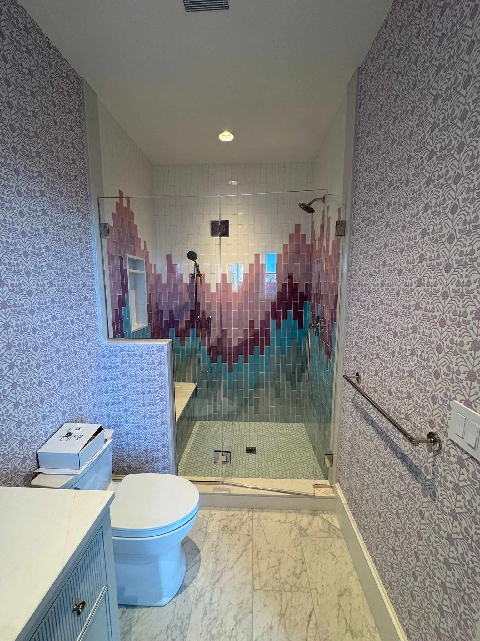 Bathroom with mosaic tile walls and shower, toilet, and vanity.