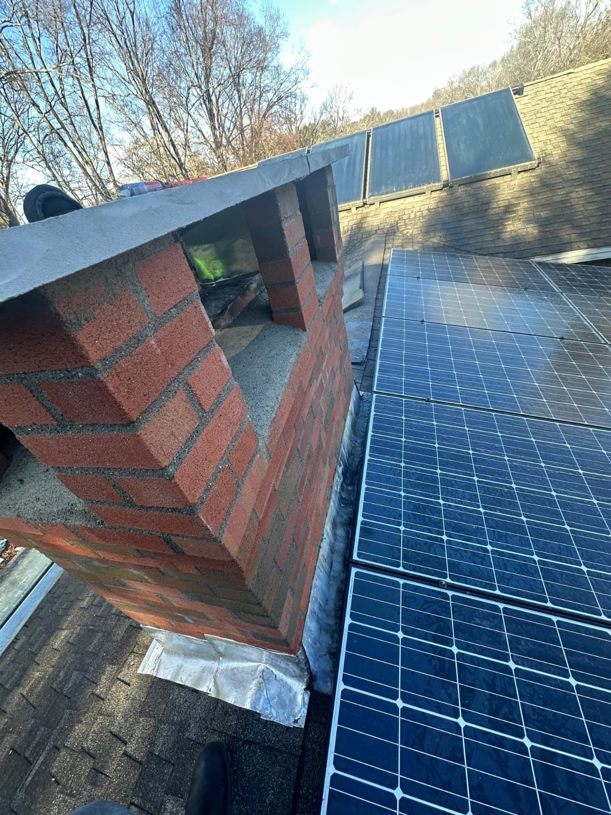 Brick chimney beside rooftop solar panels on a slanted roof