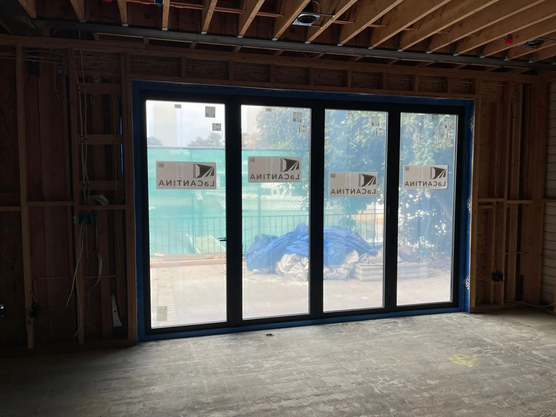 Interior view of a construction site with a large, four-pane glass door in a wooden frame.