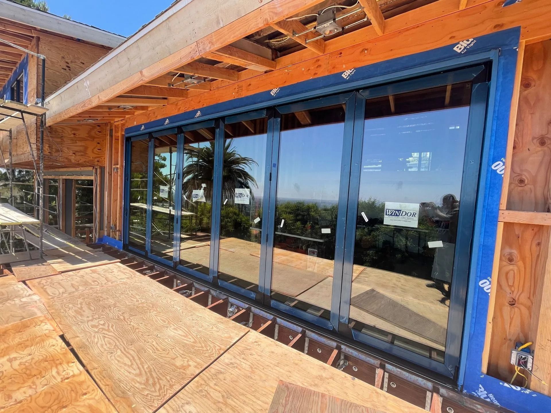 Exterior view of a house under construction with large glass sliding doors and a scenic view.