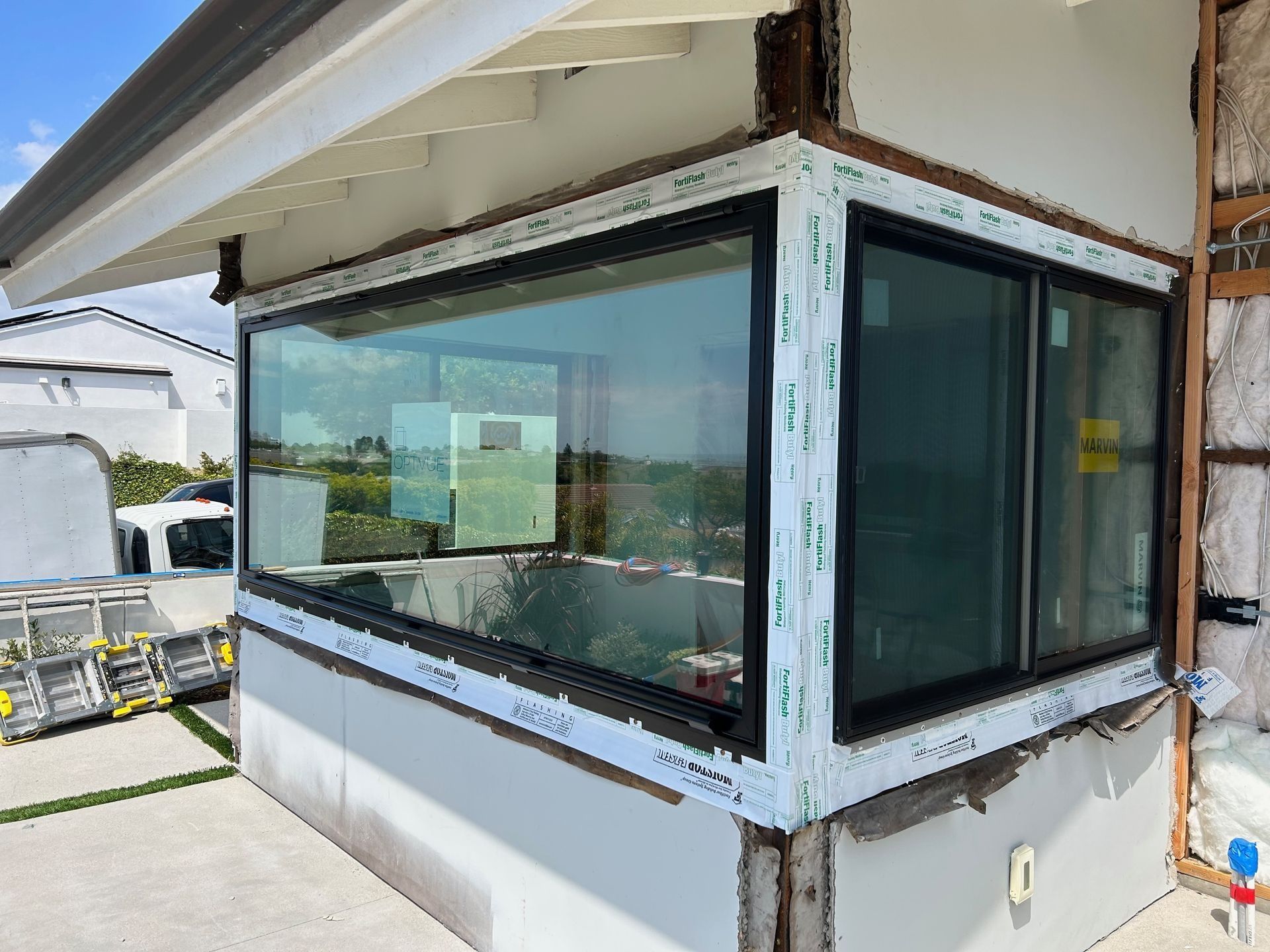 Exterior of a building with newly installed black-framed windows. White trim surrounds the windows.
