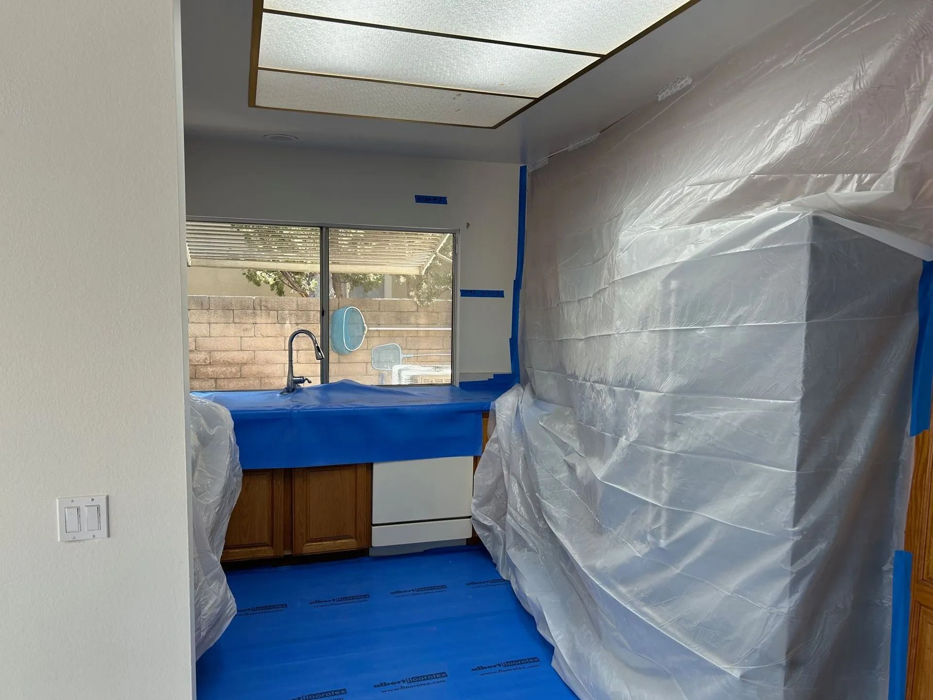 Kitchen renovation in progress: surfaces covered with blue and plastic sheeting for protection.