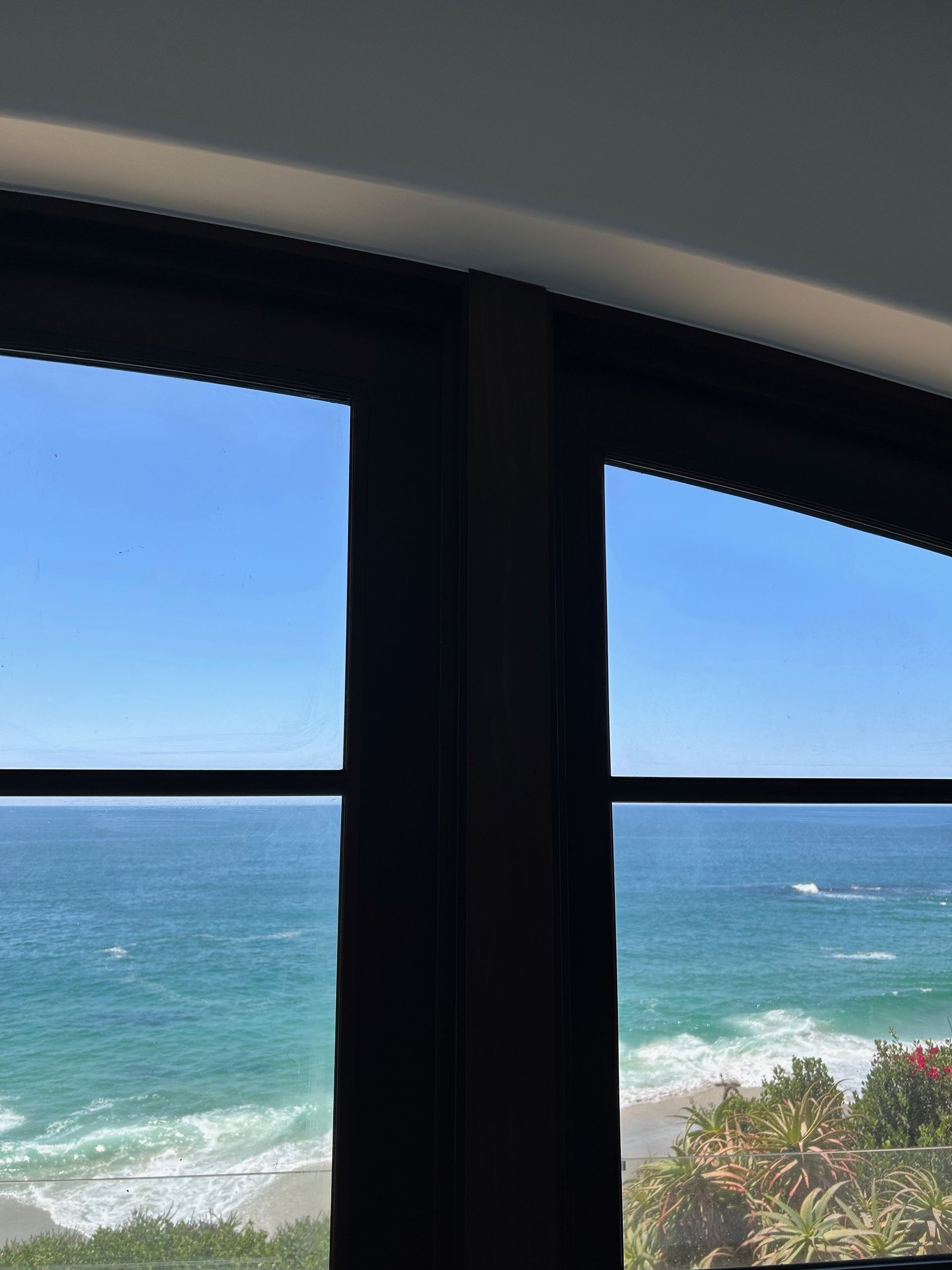 Ocean view through dark window frame, blue sky and water.